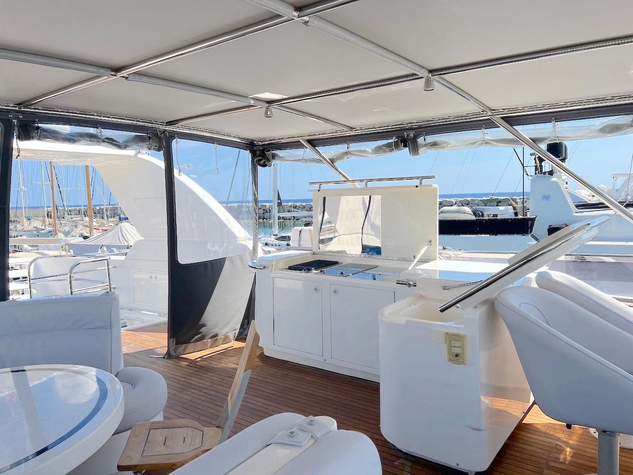 Luxurious 2001 Elegance 82 S yacht deck with seating and kitchenette, overlooking marina.