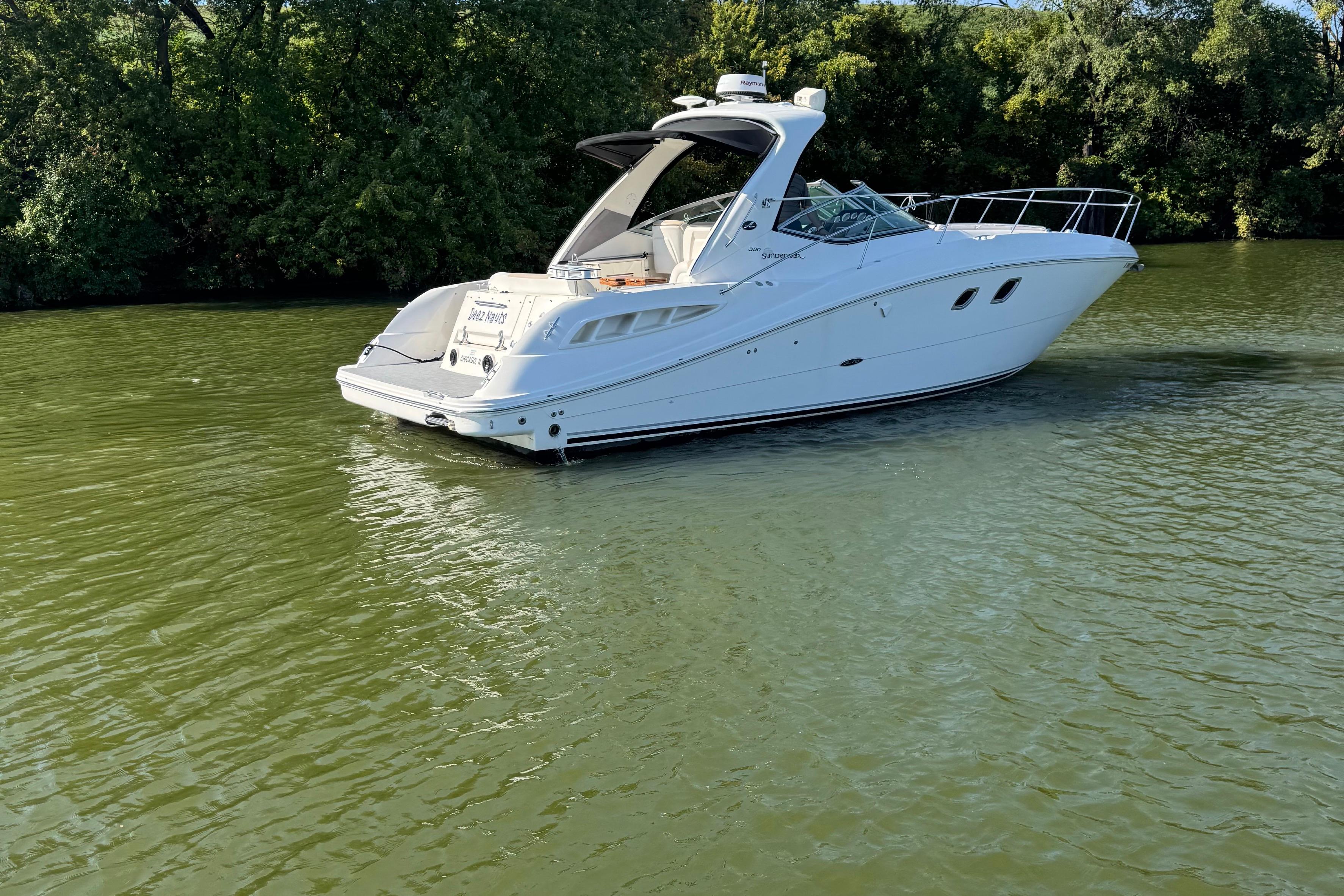 2008 Sea Ray 350 Sundancer yacht on calm green water, surrounded by lush trees.