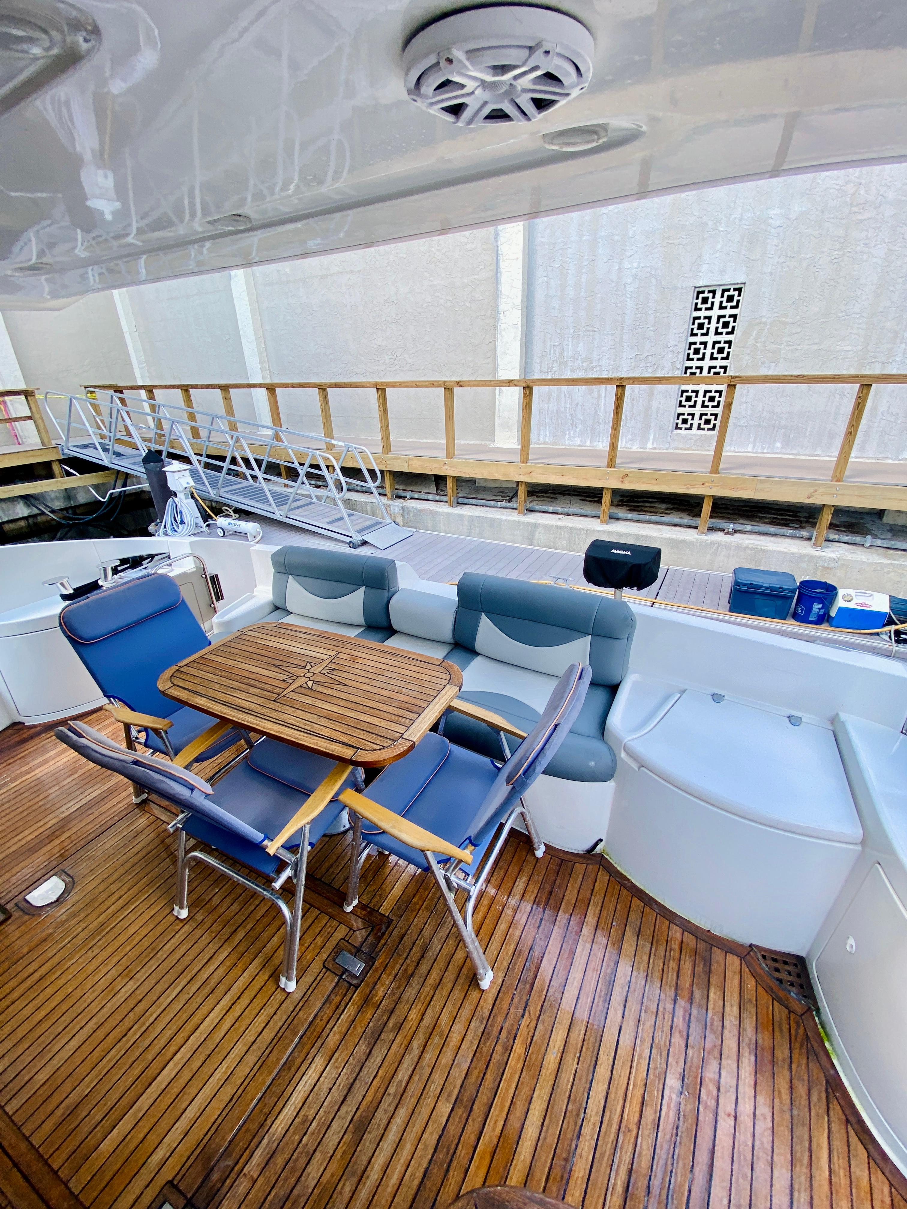 2002 Azimut 55 yacht deck with seating and wooden table.