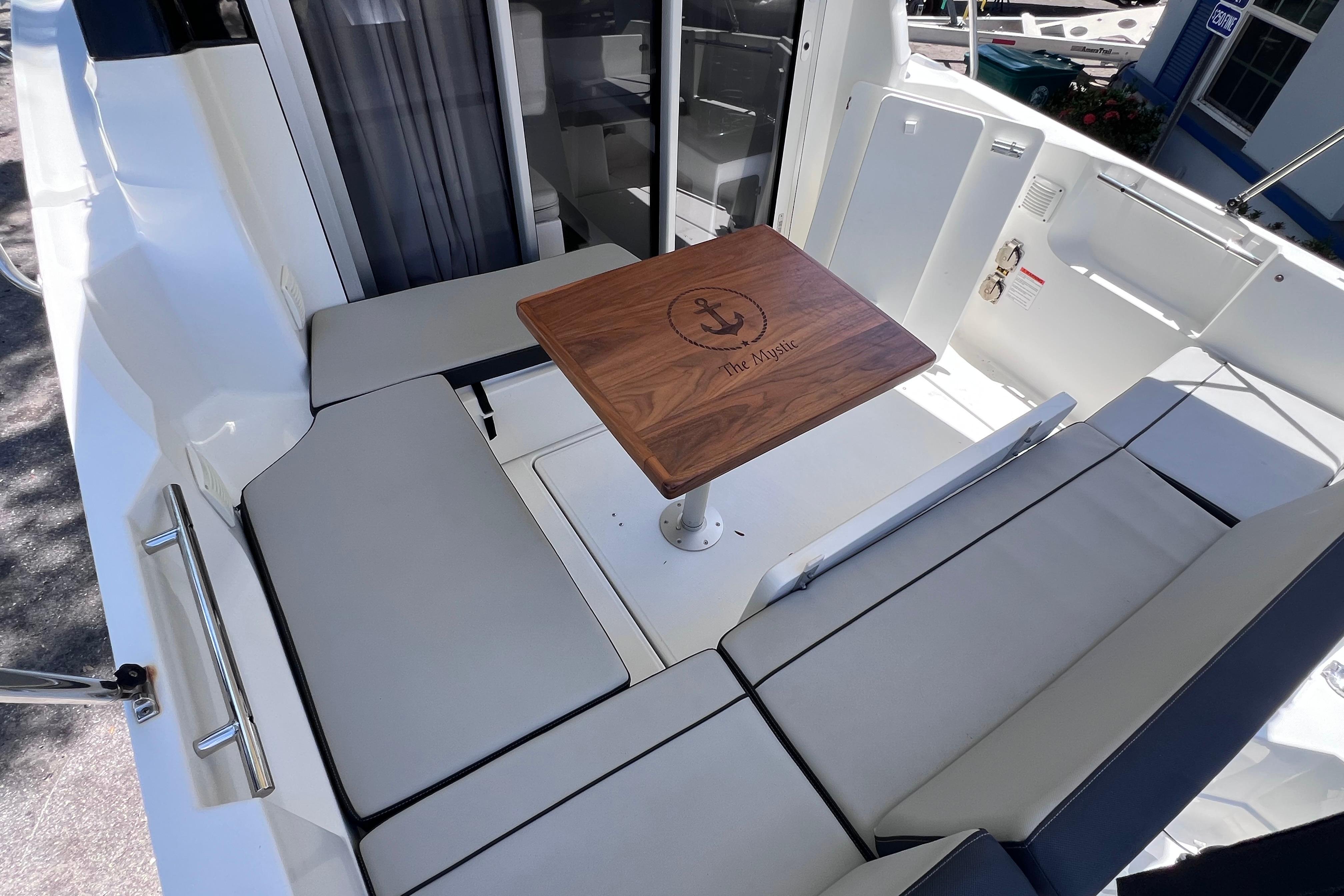 2021 Jeanneau NC Weekender 795 Series 2 boat interior with cushioned seating and wooden table.