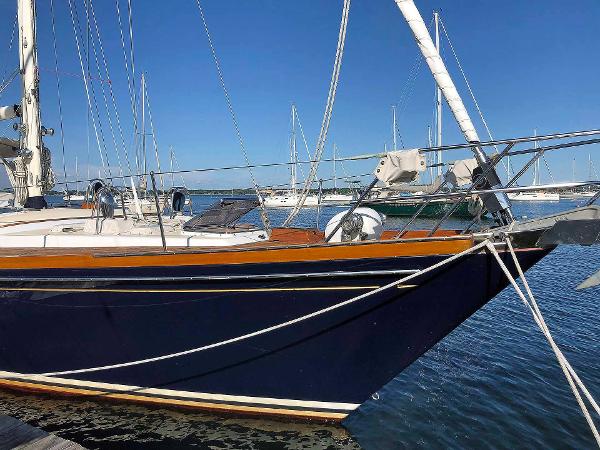 An elegant sailboat with a blue hull docked in the harbor.