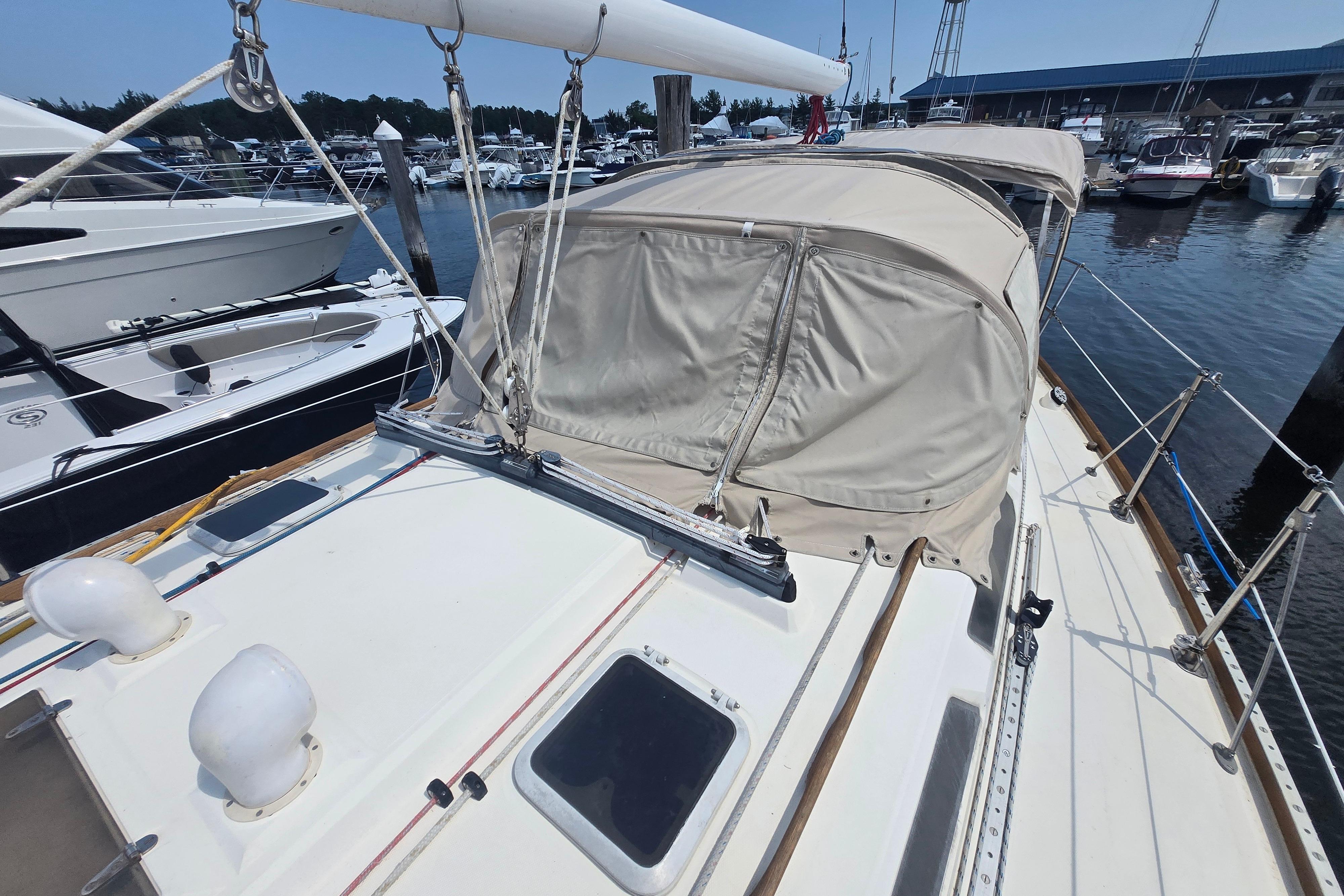 1988 Sabre 38 sailboat docked at marina, featuring beige canopy and sleek deck design.
