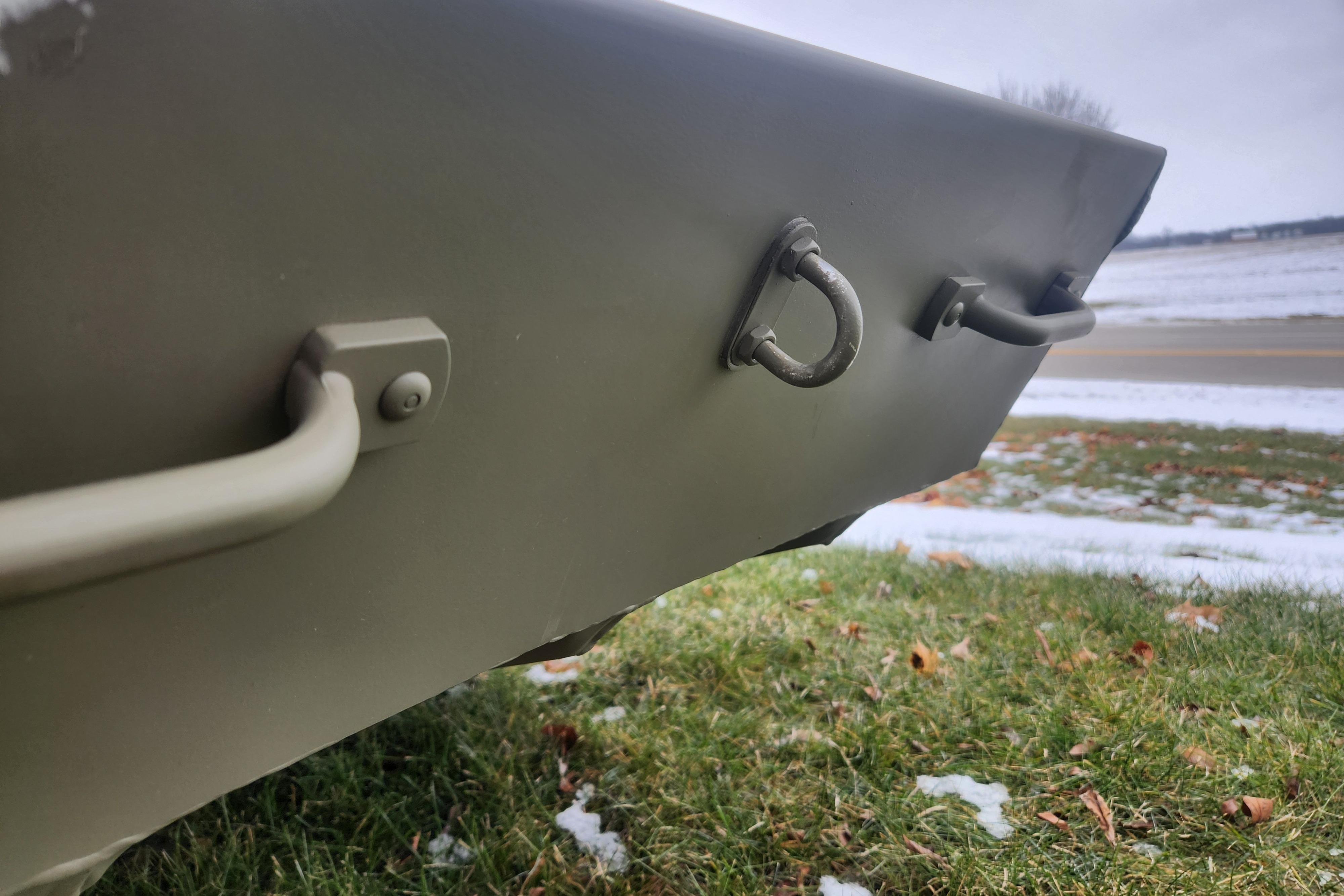 2026 Tracker Grizzly 12 Jon boat detail, showing handles and D-rings on grassy, snowy ground.