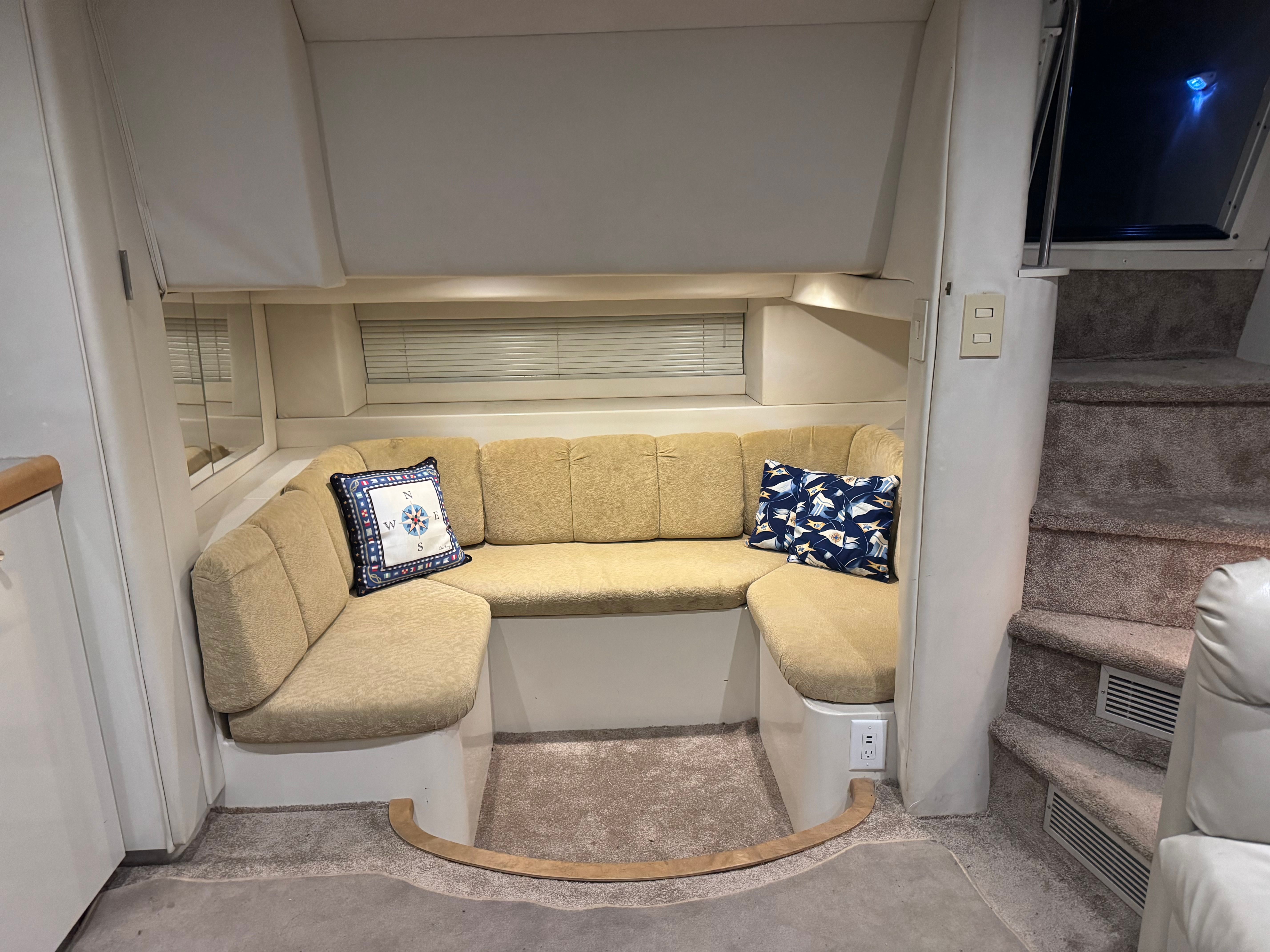 Interior of a 1995 Trojan 390x with beige sofa and decorative pillows, next to a staircase.
