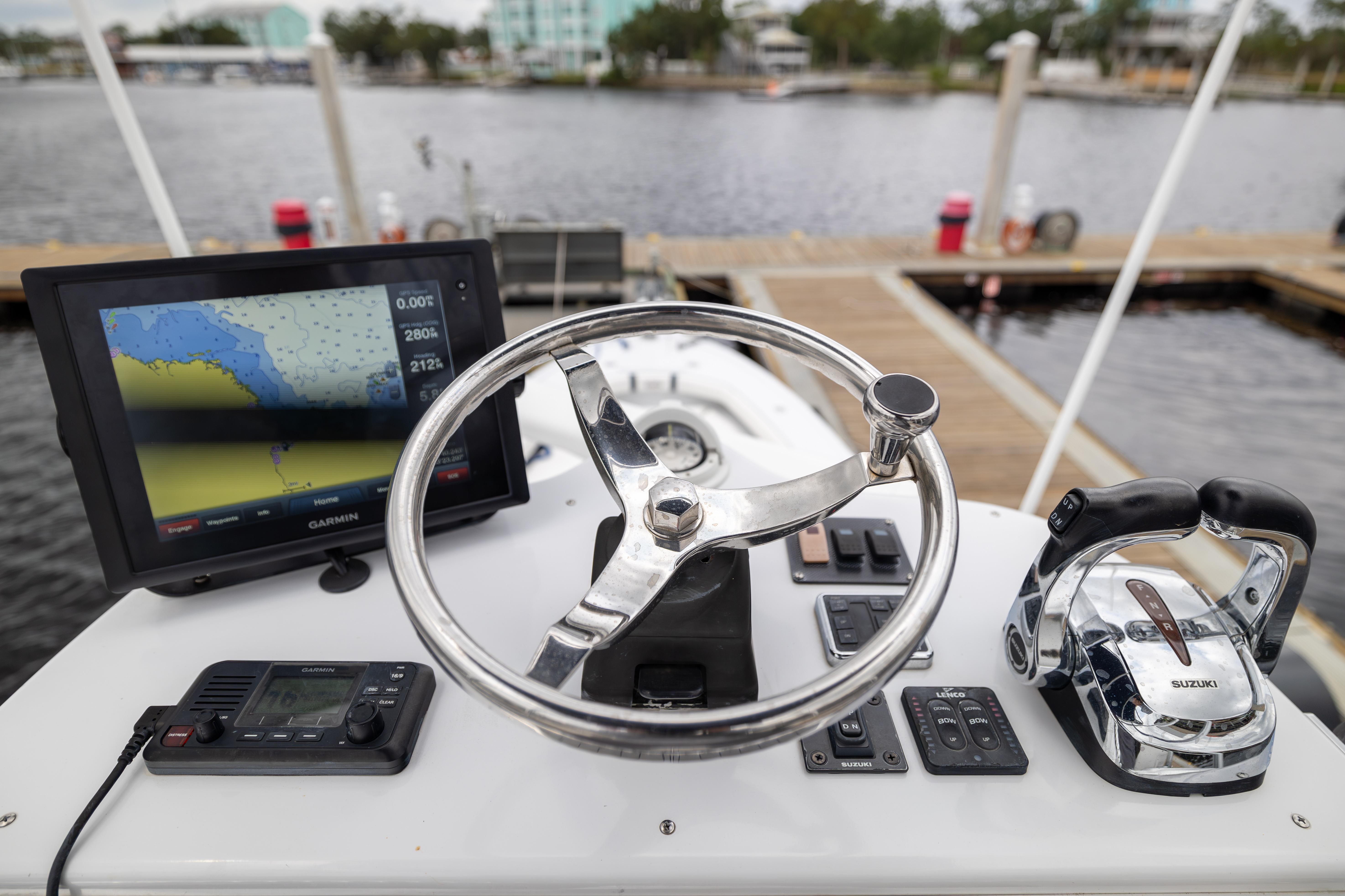 1998 Mirage Sportfish boat dashboard with Garmin navigation and Suzuki controls at a marina.