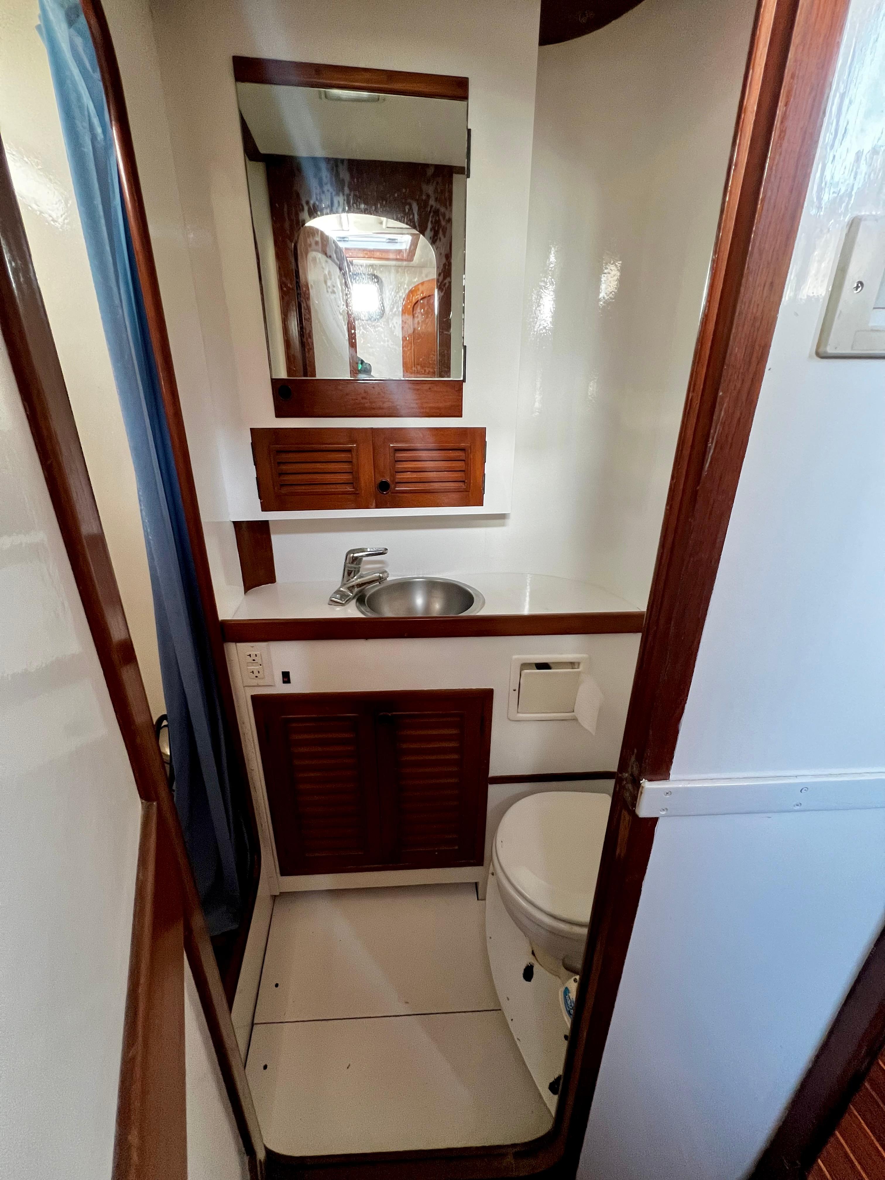 1981 Cheoy Lee Golden Wave yacht bathroom with sink, mirror, and toilet.