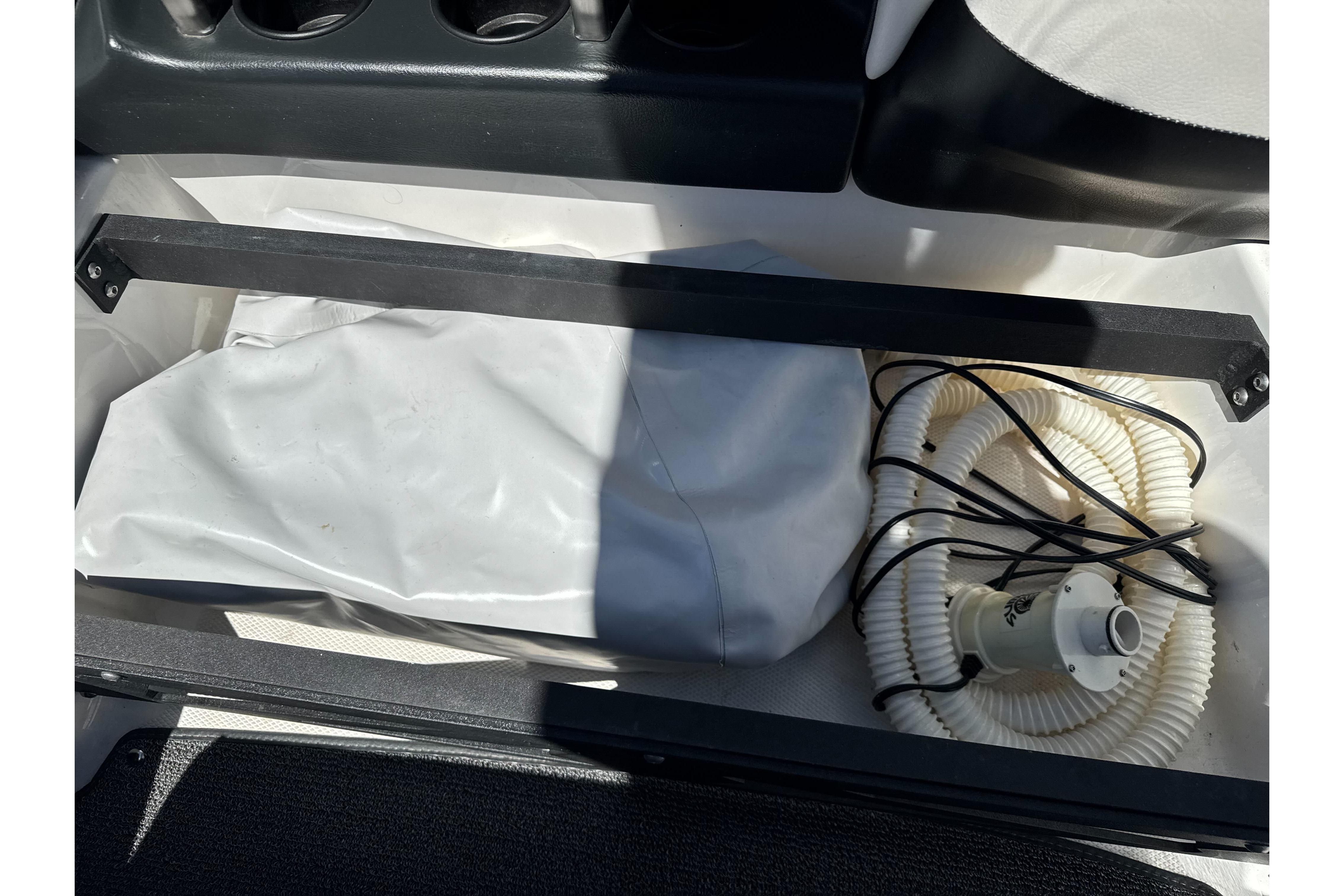 Storage compartment in a 2015 Axis A20 boat with coiled hose and cover.
