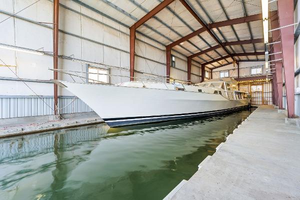 Custom 1985 Larson Boathouse with large boat docked inside spacious indoor facility.