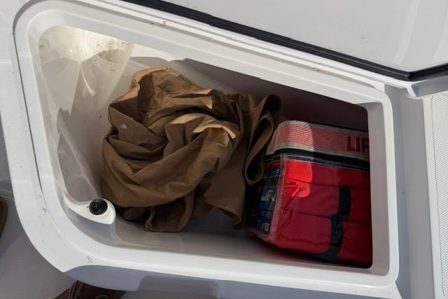Storage compartment on a 2014 Southport 29 FE boat with life jacket and tarp.