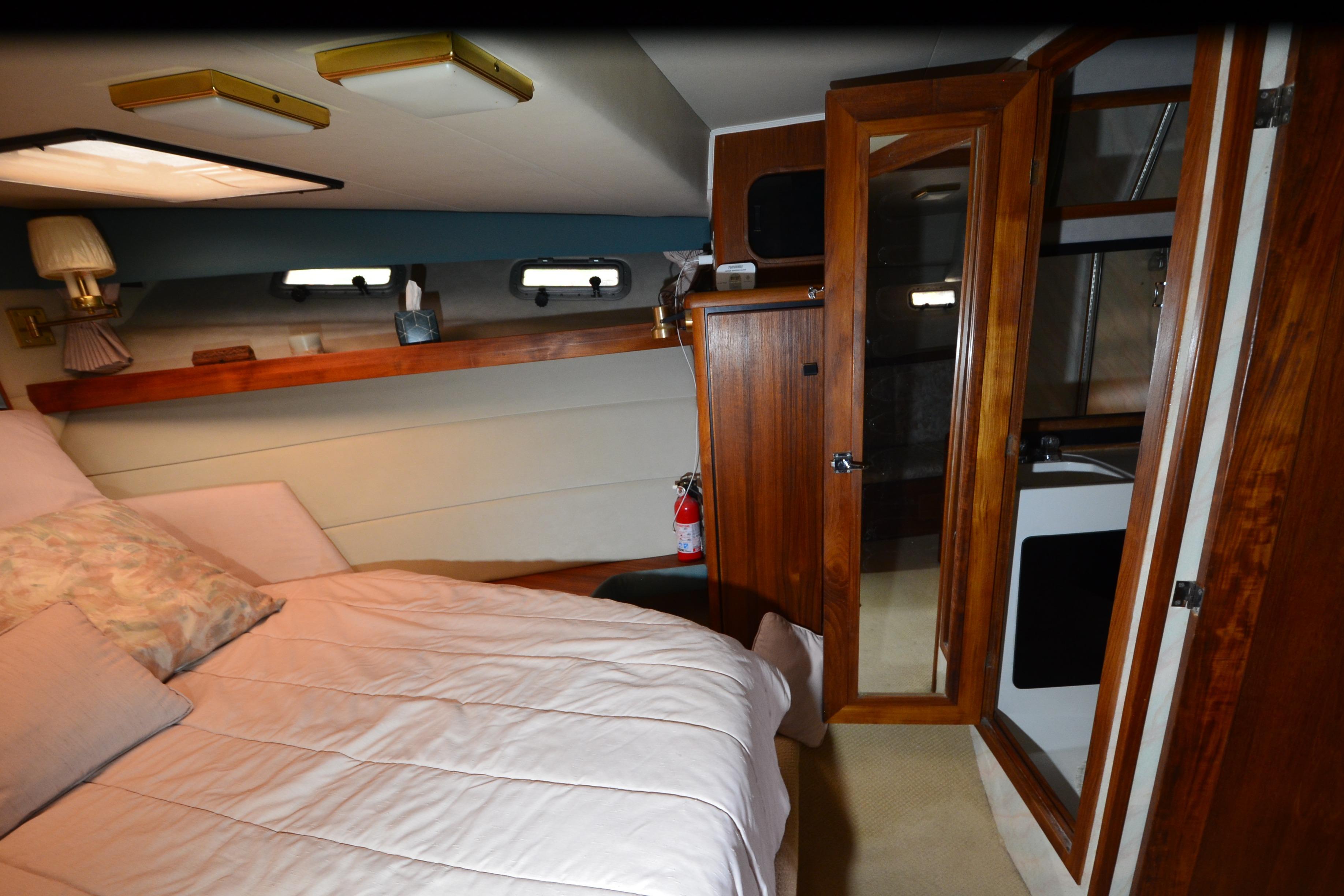 Cozy bedroom in 1989 Bayliner 4518 Motoryacht with wood accents and natural light.
