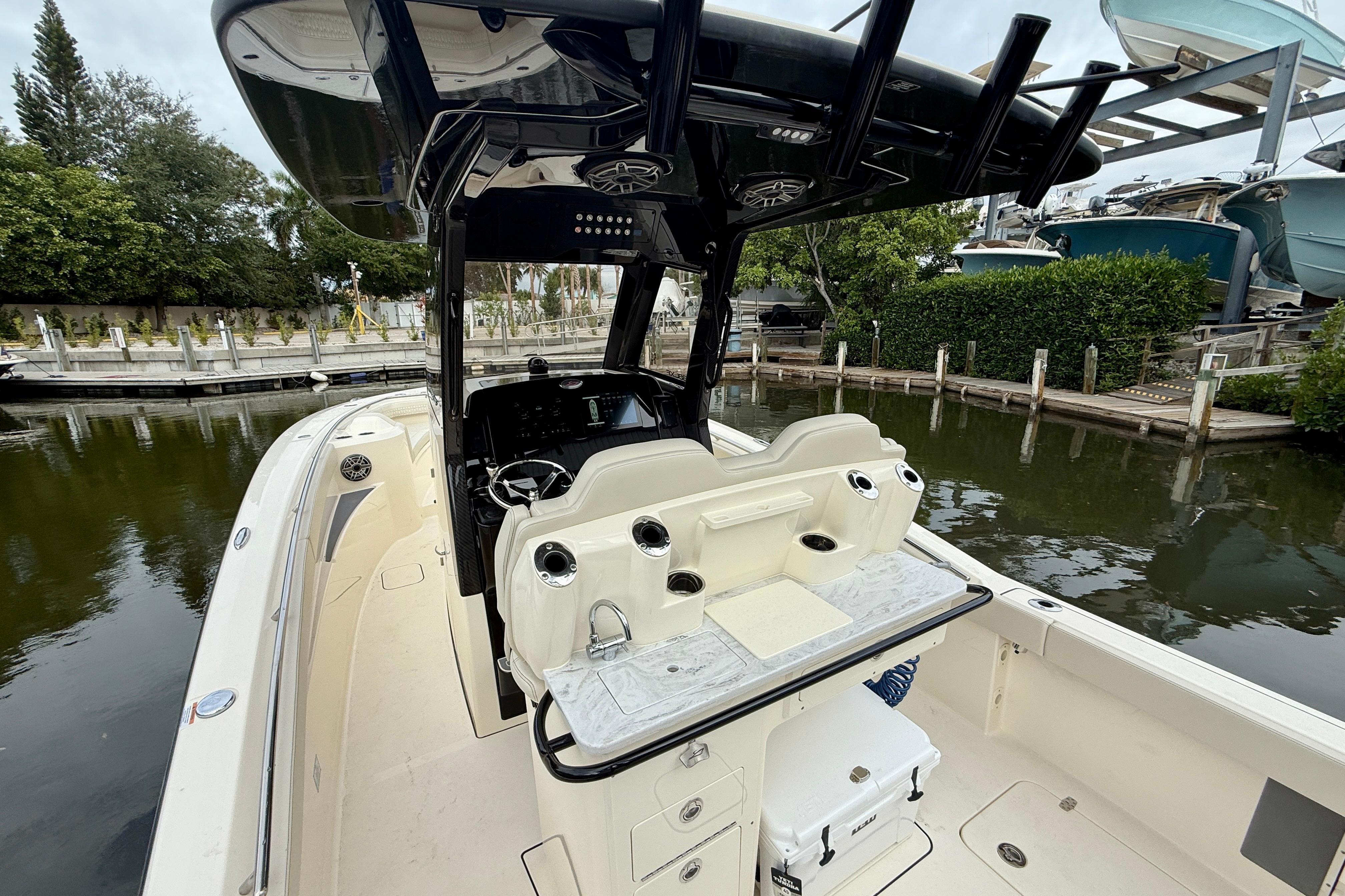 2026 Scout 288 LXF boat interior with helm and seating, docked by lush greenery.