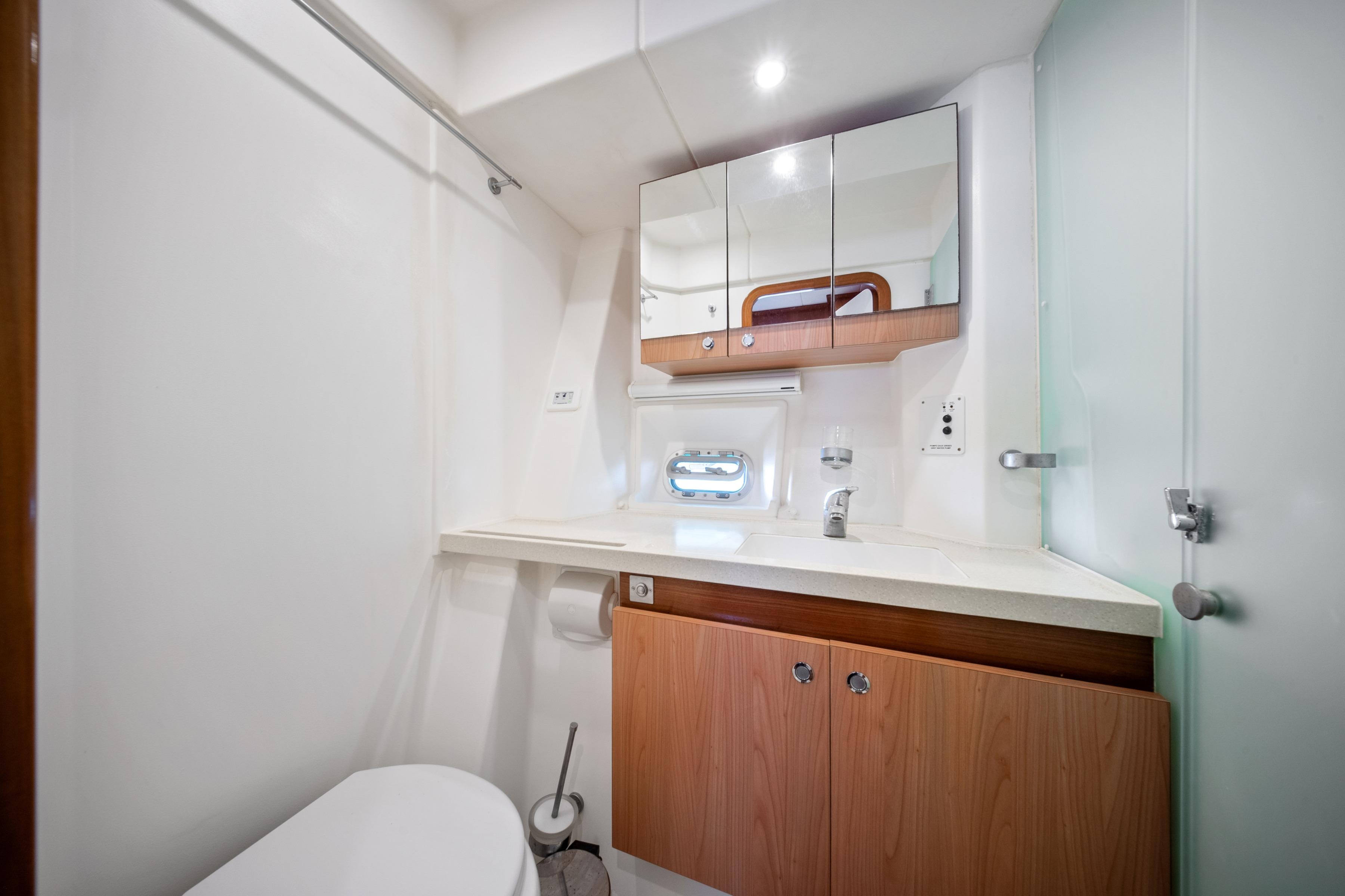 Luxurious bathroom in a 2009 Catana 65 yacht, featuring modern fixtures and wooden cabinetry.