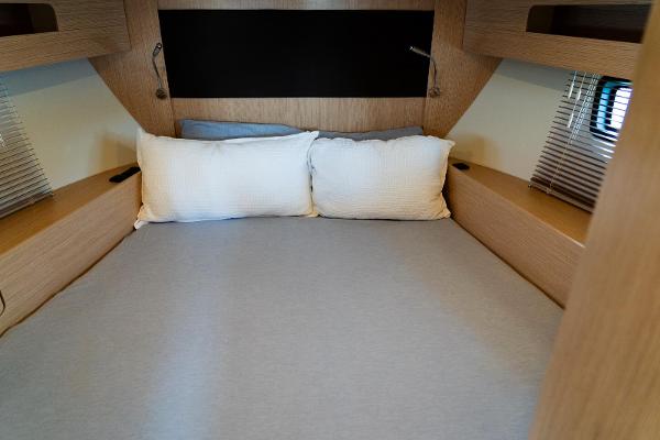 Cozy cabin bed in 2022 Bavaria SR41 yacht with wooden accents and soft pillows.