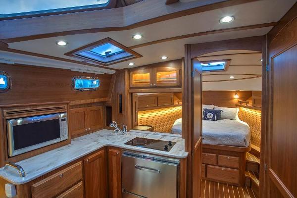 Interior of a luxury yacht with kitchen and sleeping area, wood finish, and skylights.