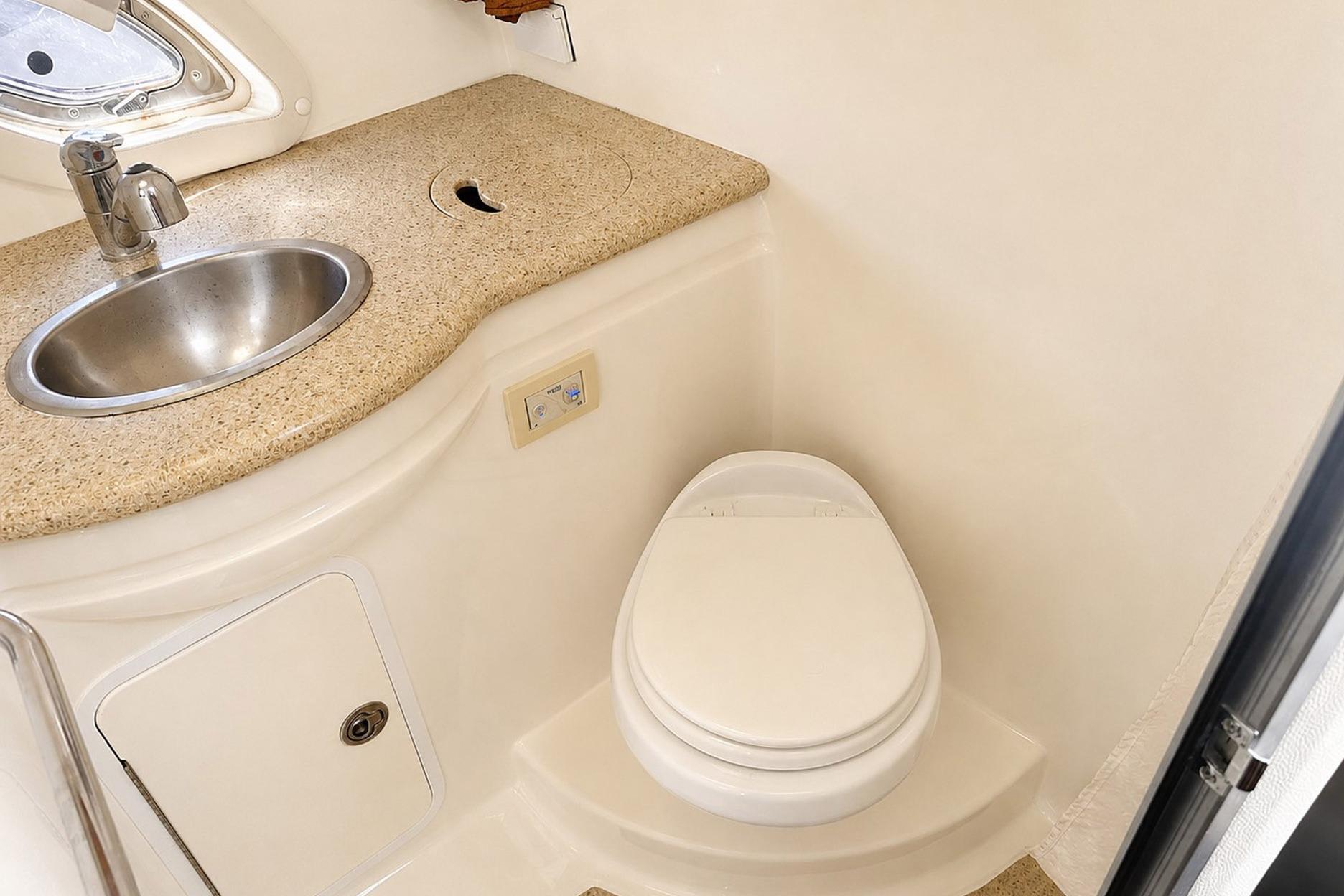 Bathroom interior of 2012 Rinker 310 Express Cruiser LE with sink and toilet.