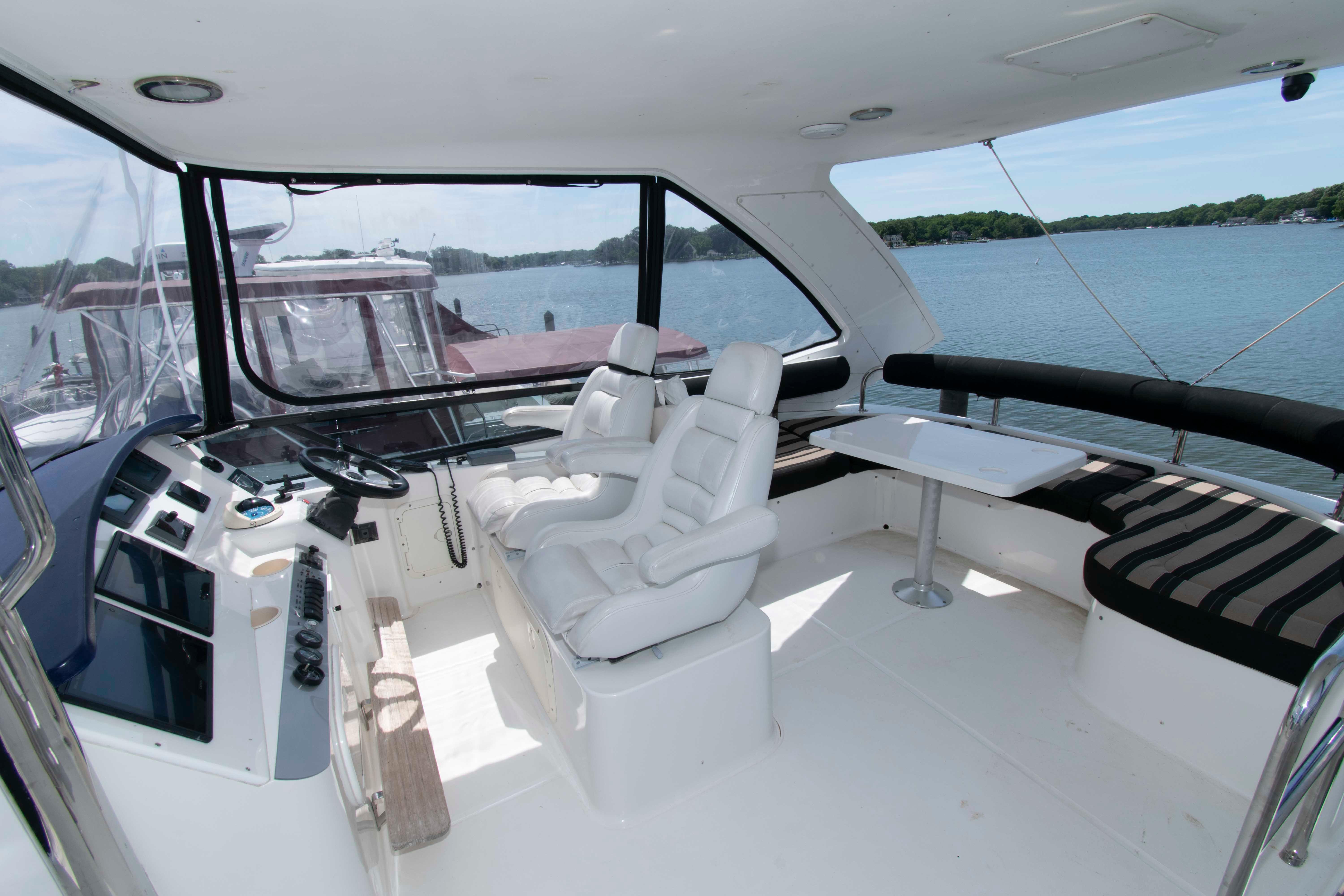 Flybridge of 2003 Neptunus 56 yacht with helm, seating, and table overlooking water.