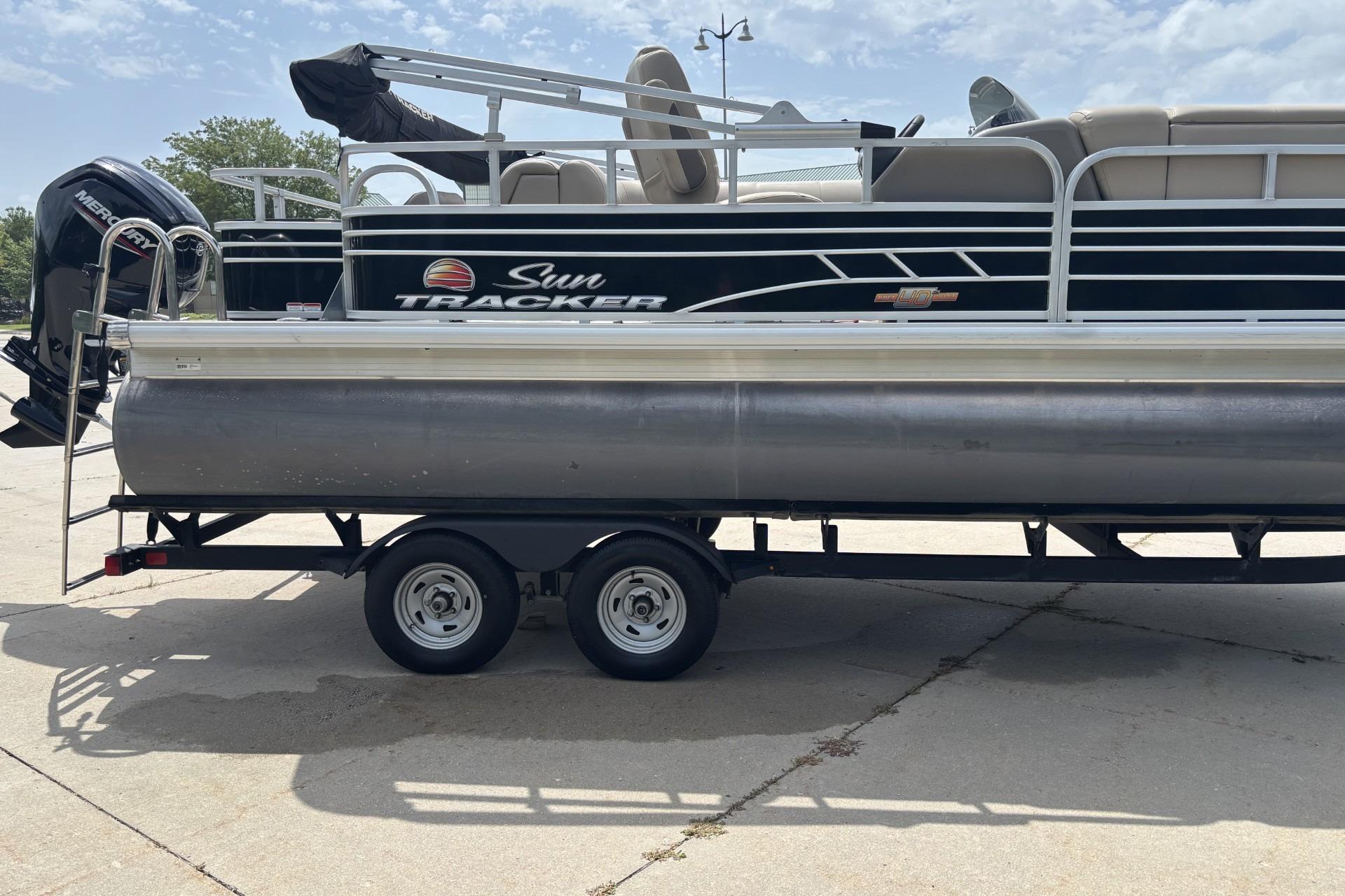 2023 Sun Tracker SportFish 20 DLX pontoon boat on trailer, side view.