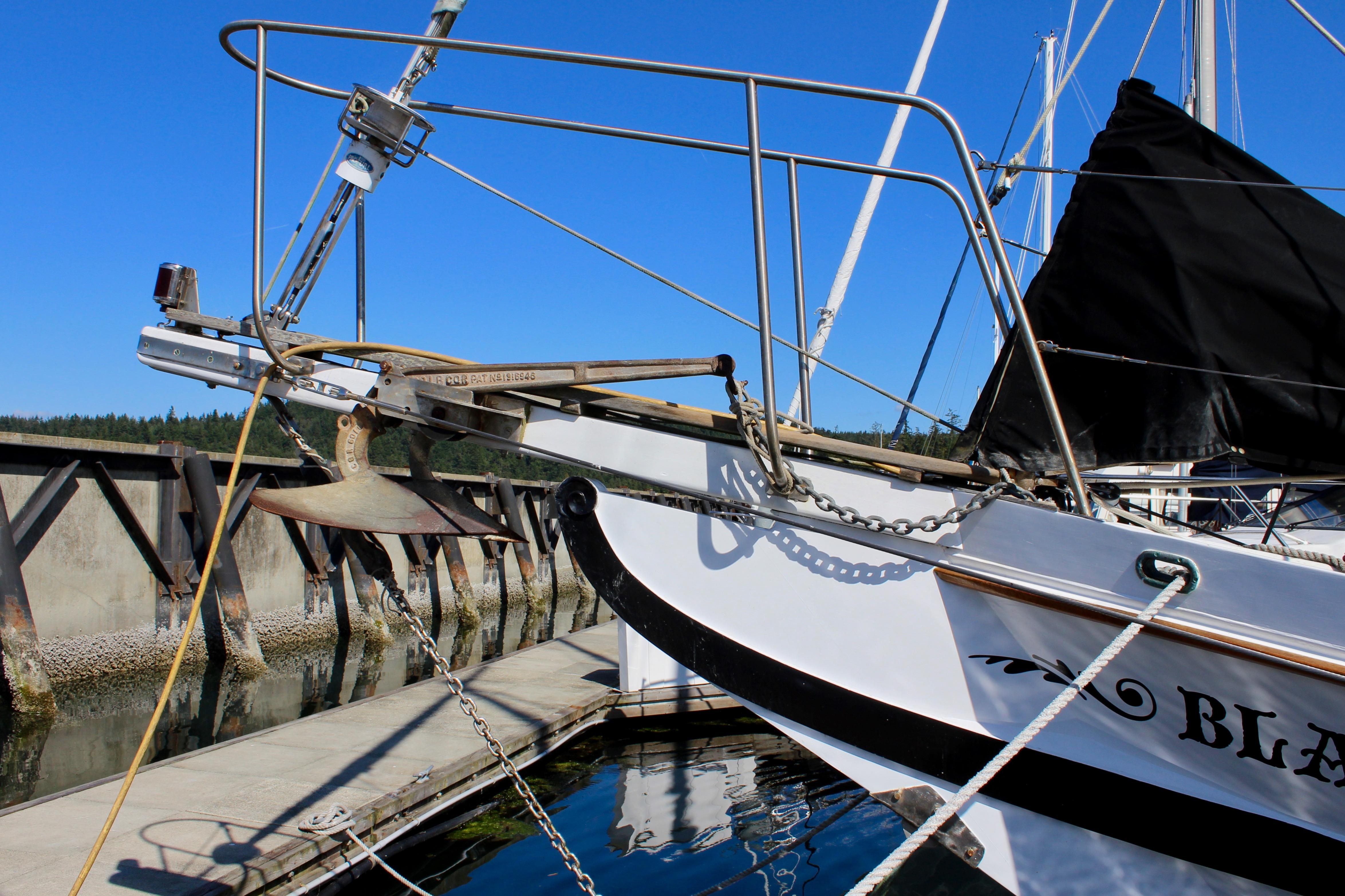 1975 William Garden Porpoise sailboat docked, featuring anchor and rigging against clear blue sky.