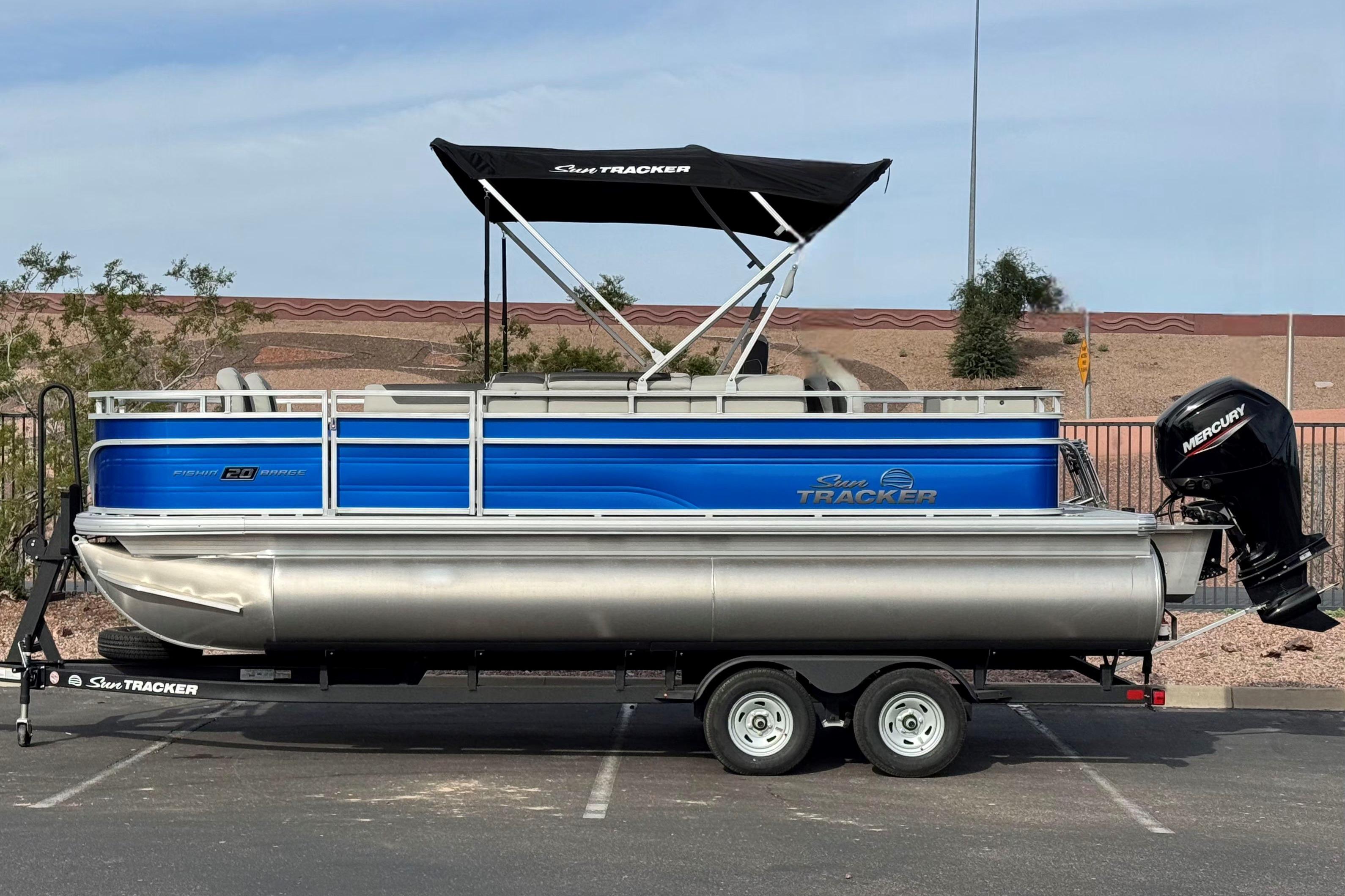 2026 Sun Tracker Fishin' Barge 20 DLX pontoon boat on trailer, side view.