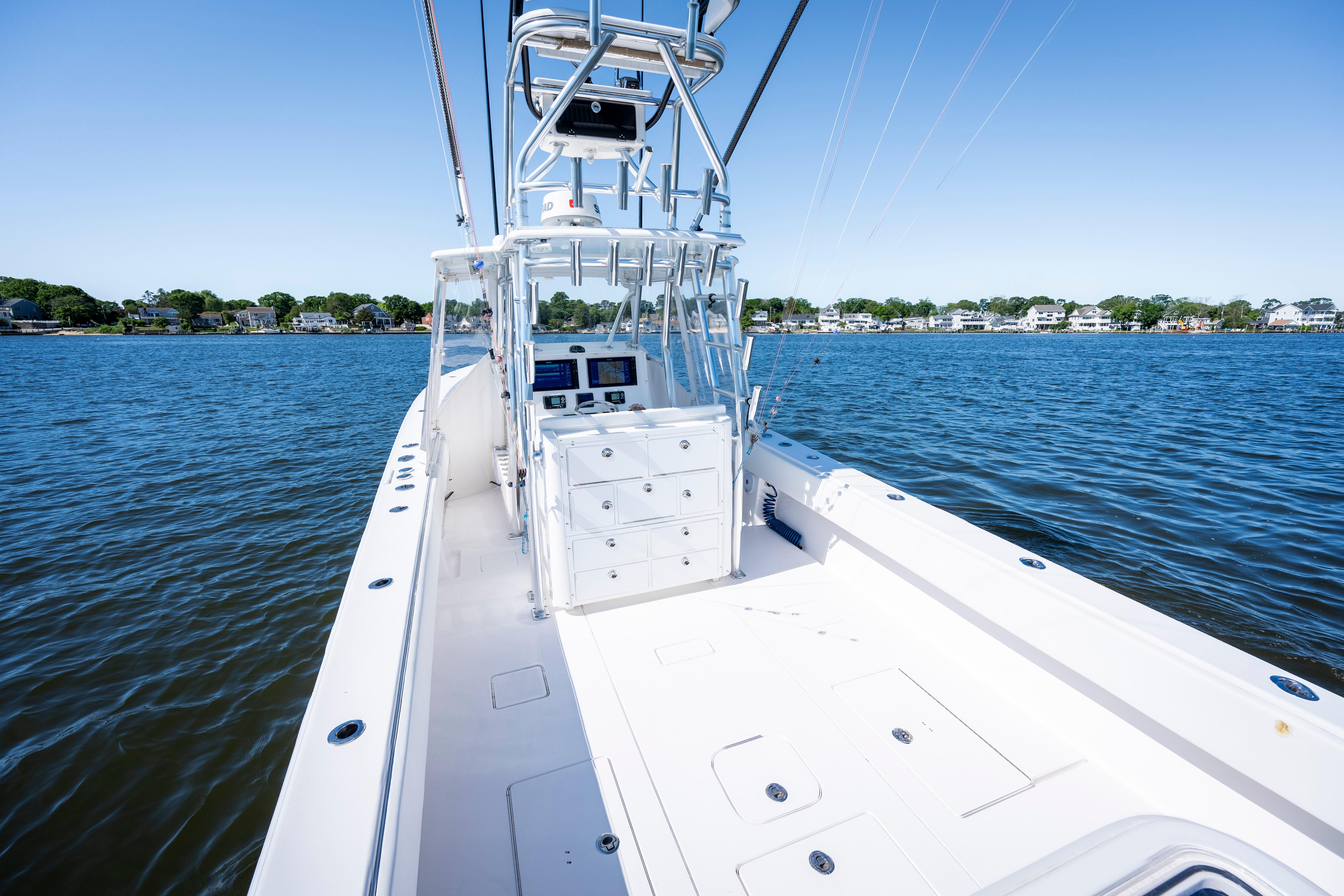 2015 Contender 39 ST boat on calm water, clear sky, coastal background.