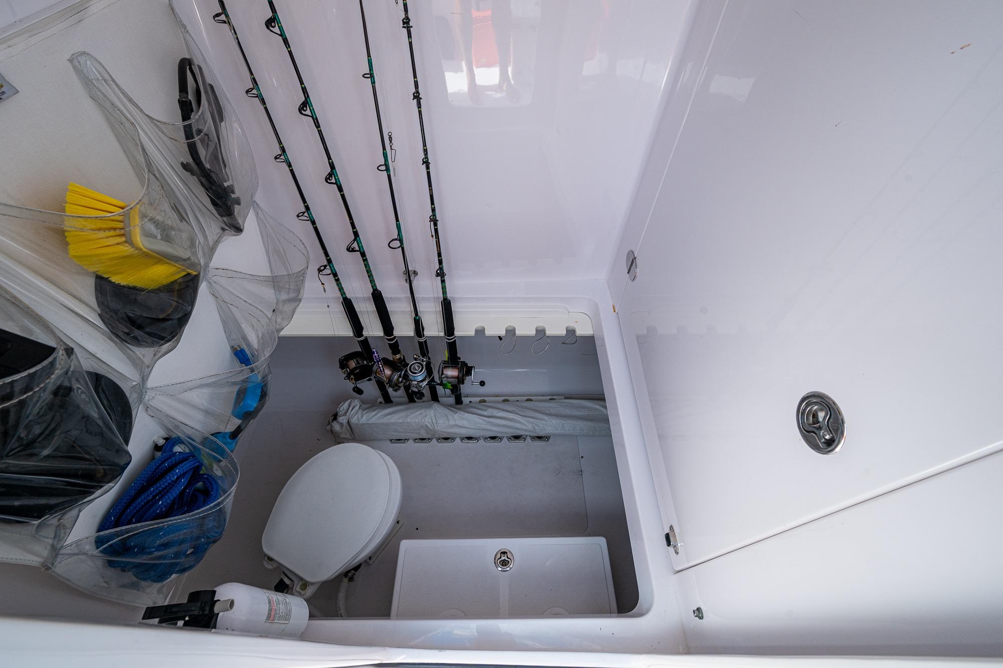 2015 Bahama 41 boat storage area with fishing rods, toilet, and cleaning supplies.