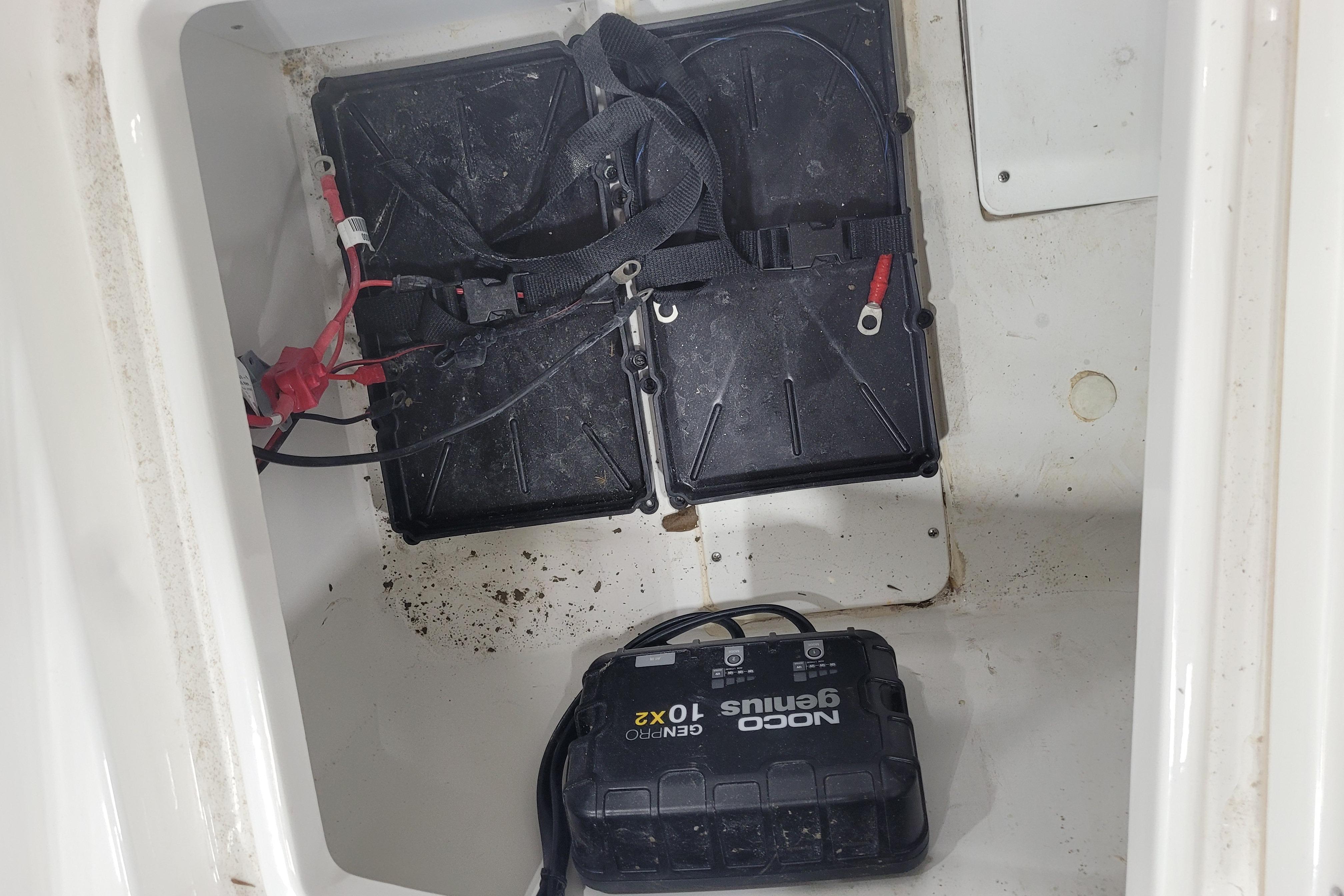 Battery compartment of a 2026 Tahoe 2150 boat with NOCO Genius charger.