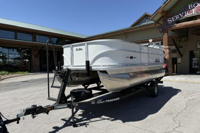 2026 Sun Tracker Party Barge 18 DLX pontoon boat on trailer outside service center.