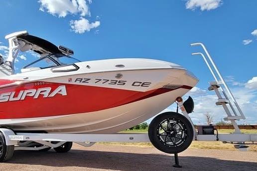 2023 Supra SE 550 boat on trailer under blue sky.
