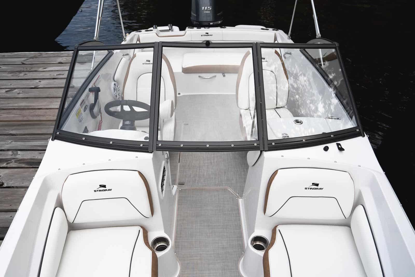 Manufacturer Provided Image: 2026 Stingray 191 DC boat interior with seating and steering wheel, docked by wooden pier.