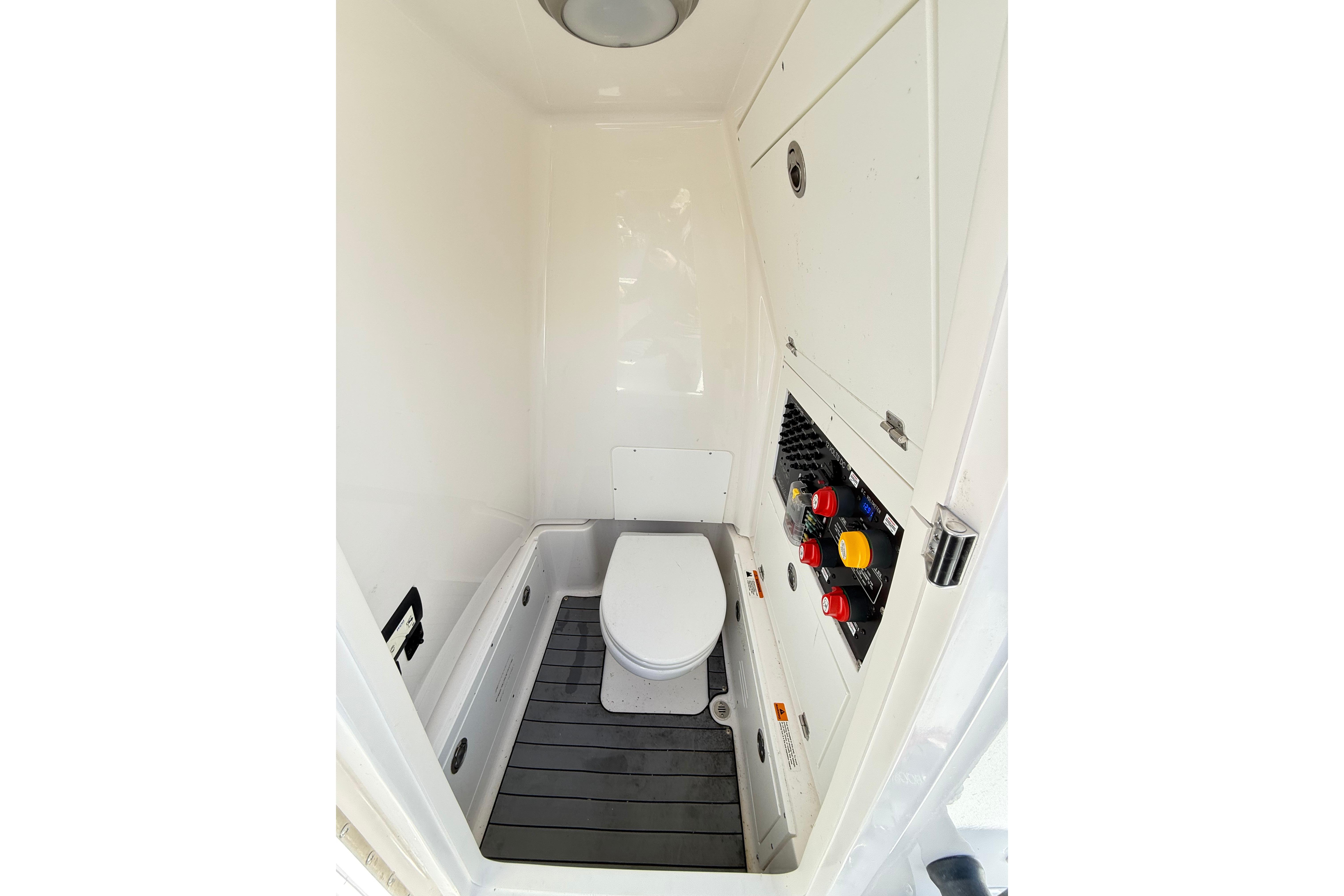 2023 Caymas 281 HB boat interior with compact marine toilet and control panel.