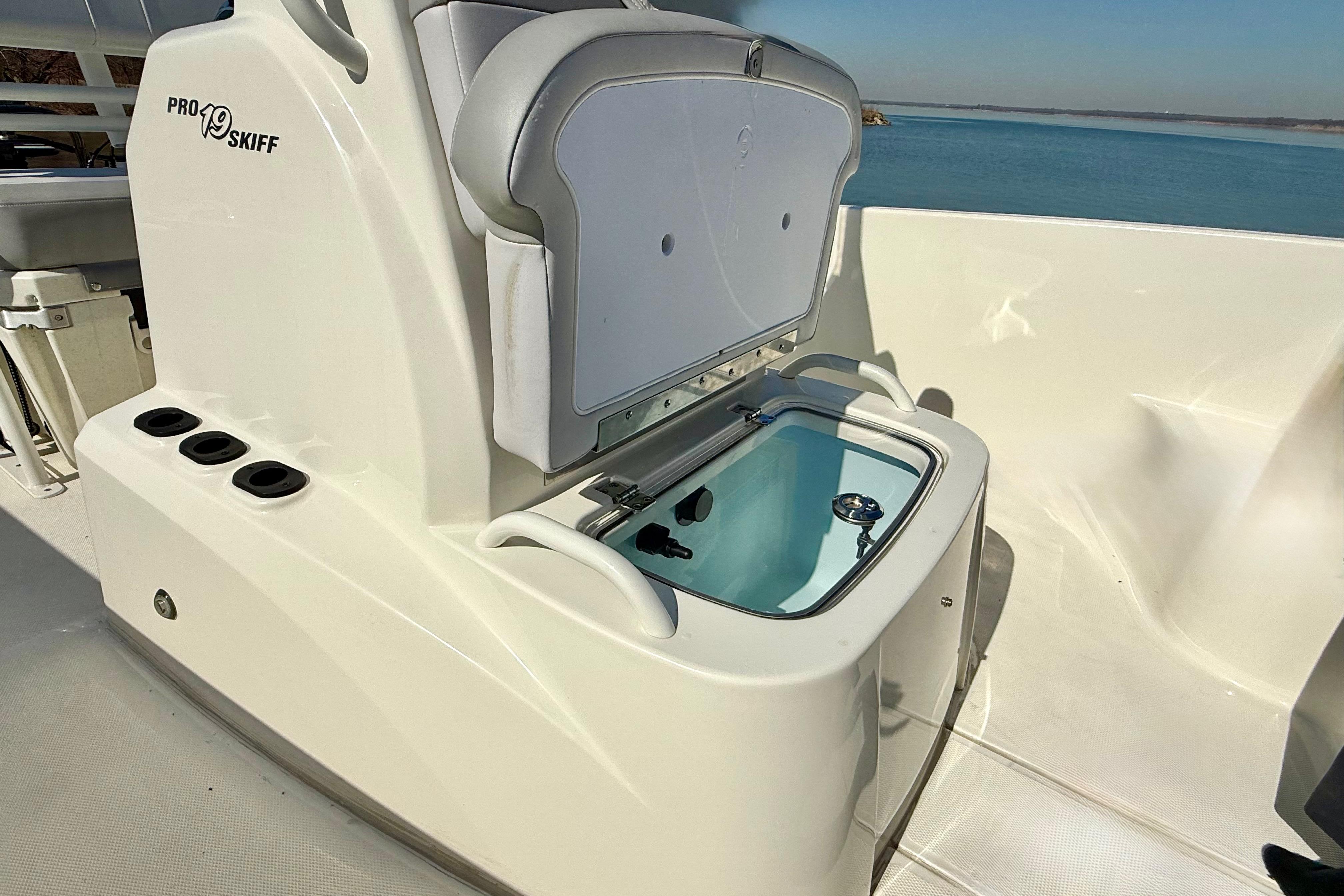 2024 Mako Pro Skiff 19 CC boat with open storage compartment, docked by the water.