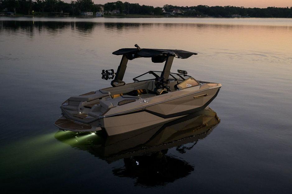 Manufacturer Provided Image: 2026 Nautique Super Air Nautique G23 boat on calm water at sunset with lights on.