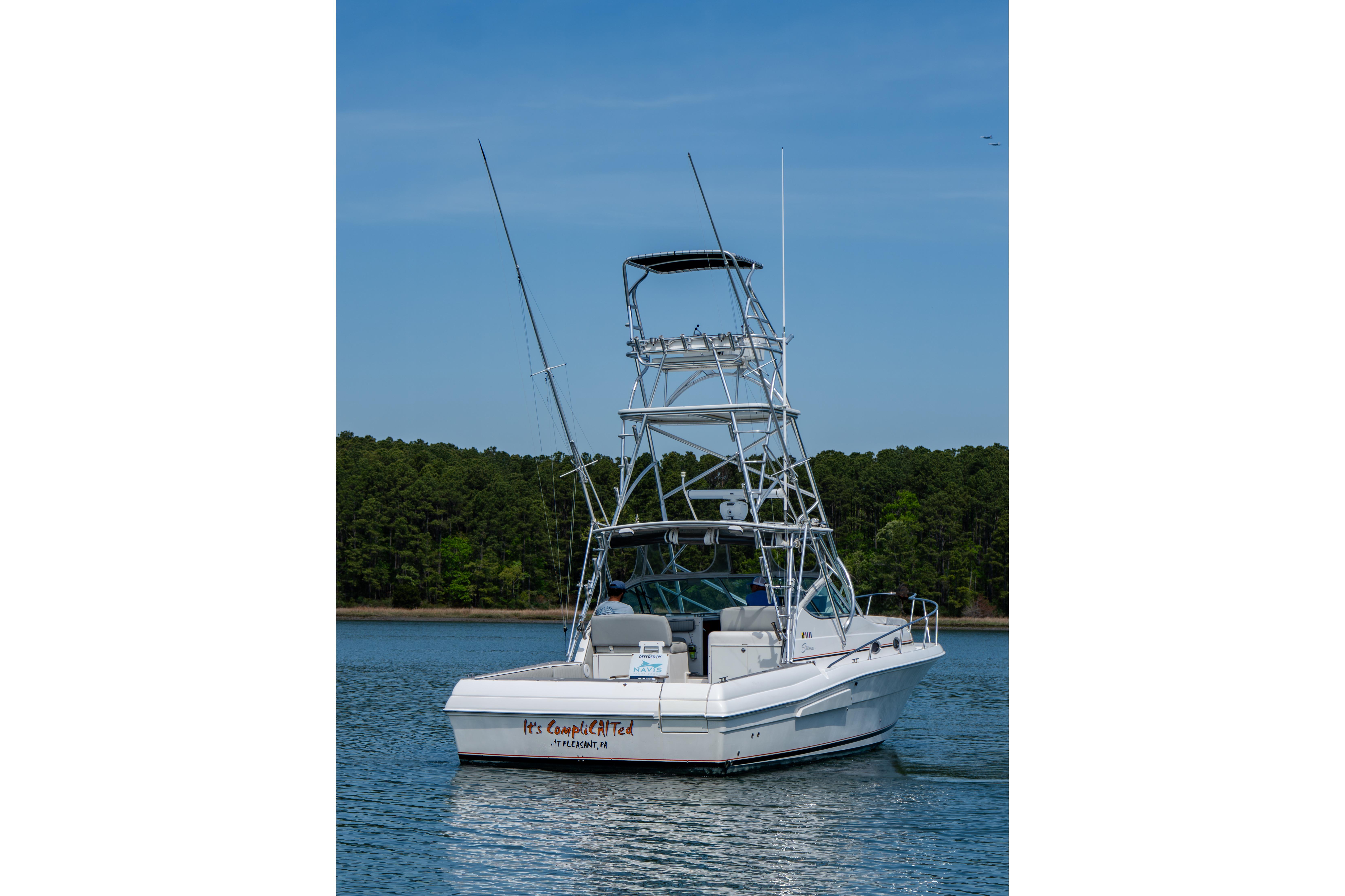 2004 Stamas 370 Express boat on calm water with forested shoreline.