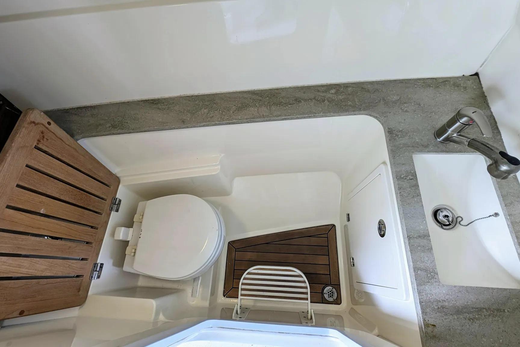 2017 Boston Whaler 320 Vantage boat bathroom with toilet, sink, and wooden accents.