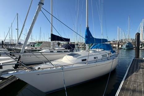1985 Sabre 32 sailboat docked at marina, surrounded by other boats under clear blue sky.