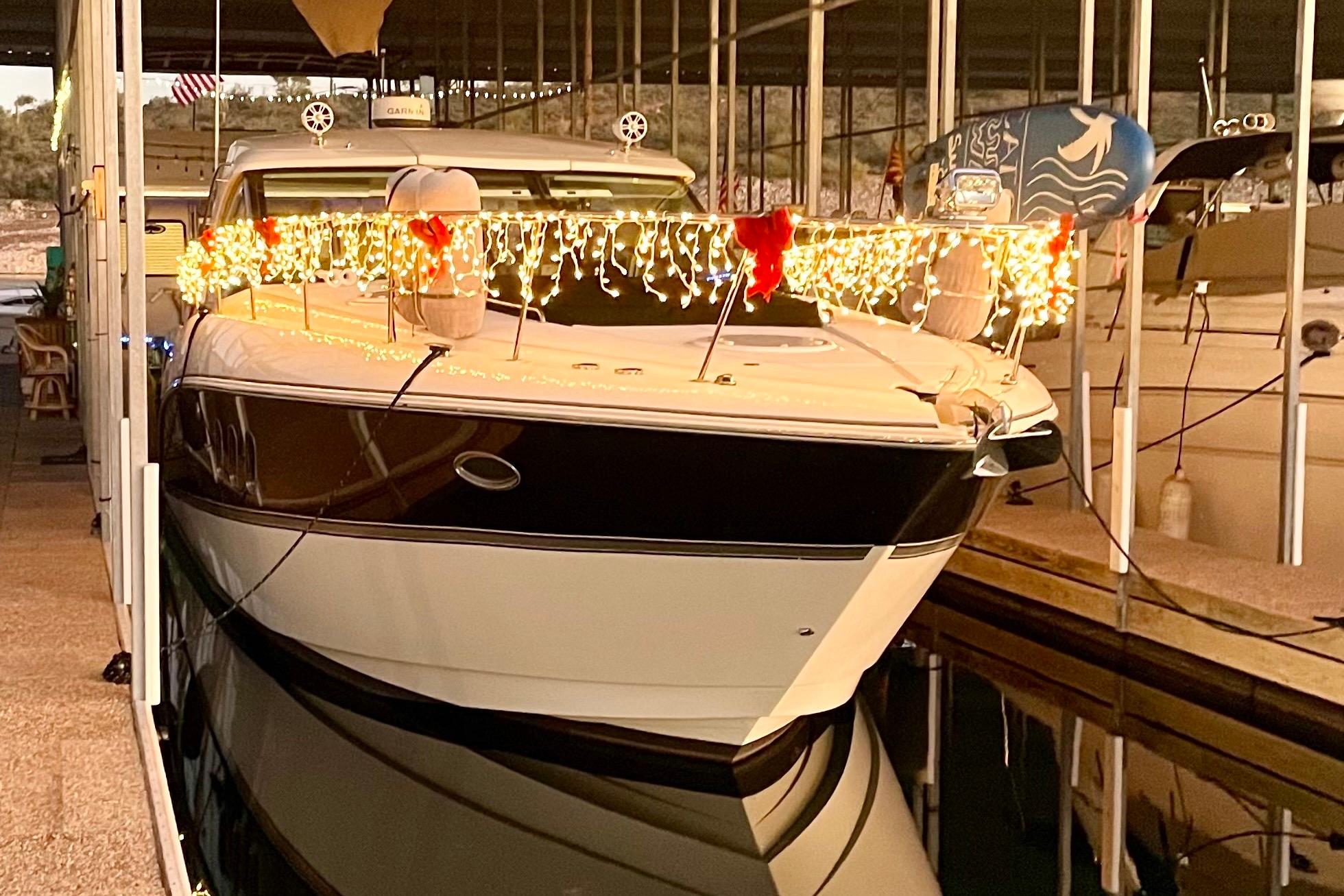 2011 Cruisers Yachts 390 Sports Coupe decorated with festive lights in a marina.