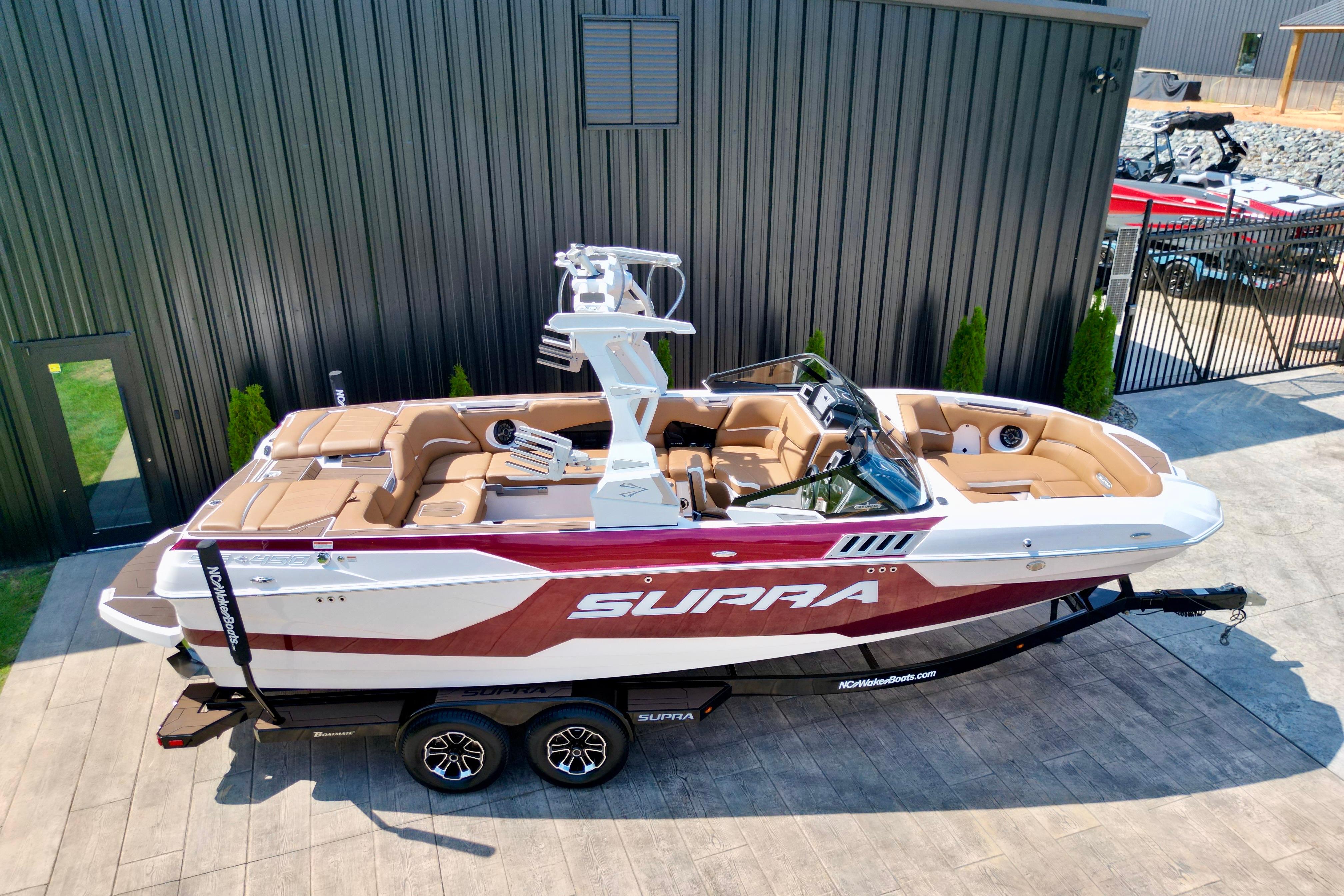 2021 Supra SE boat with sleek design, parked on a trailer near a modern building.