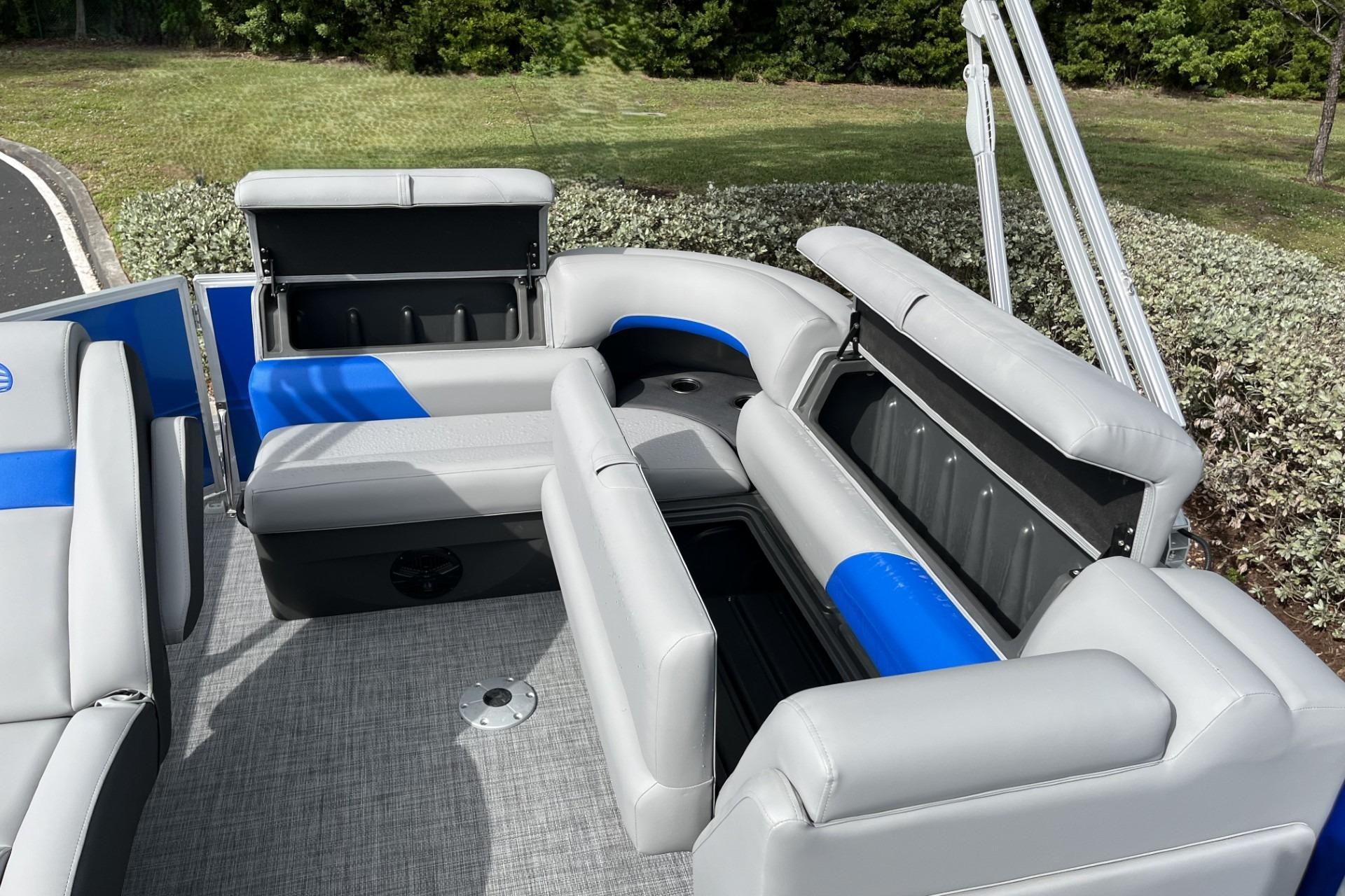 2026 Sun Tracker Party Barge 20 DLX interior with gray and blue seating, open storage compartments.