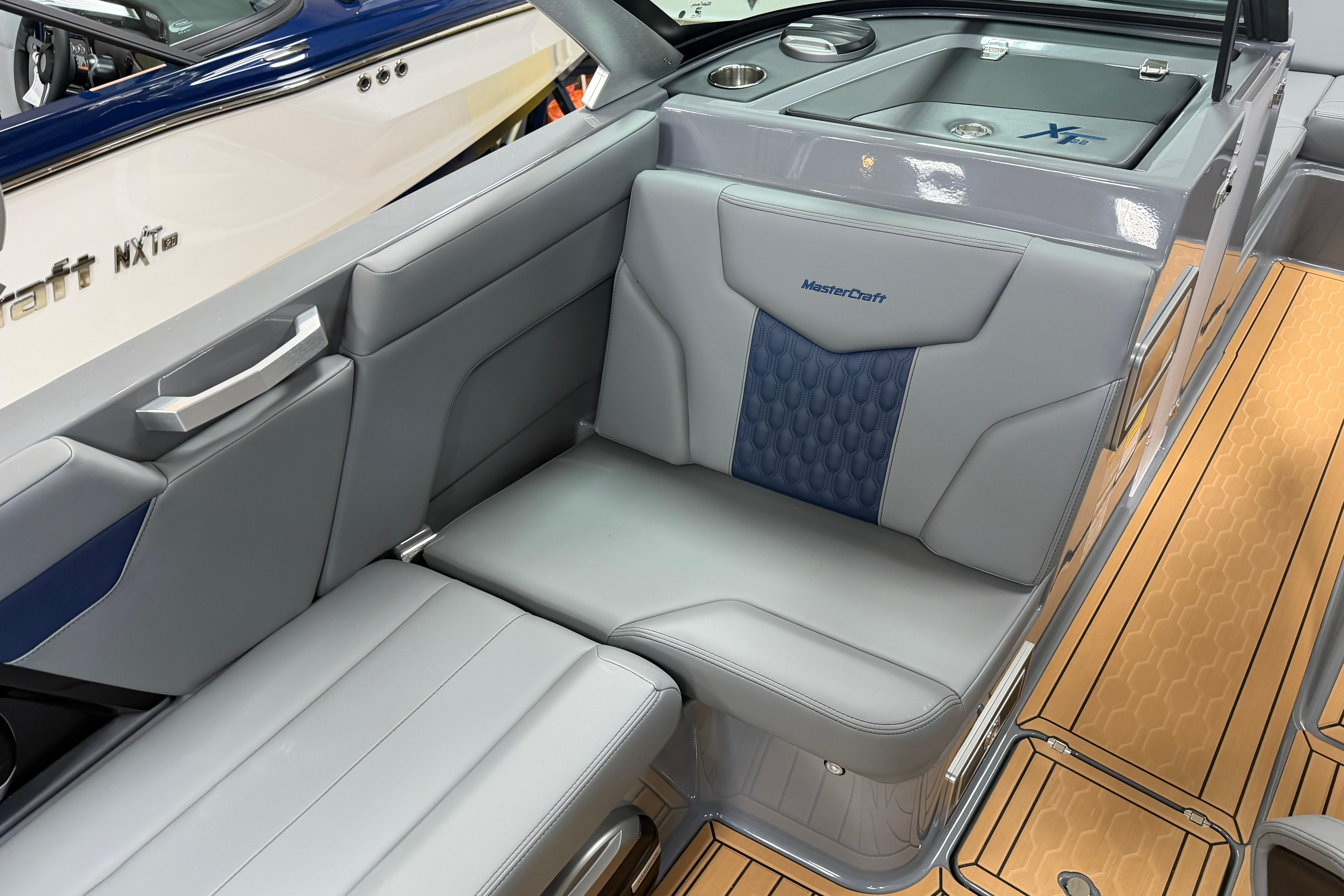 2026 MasterCraft XT22 boat interior with gray and blue seating, wood-patterned flooring.