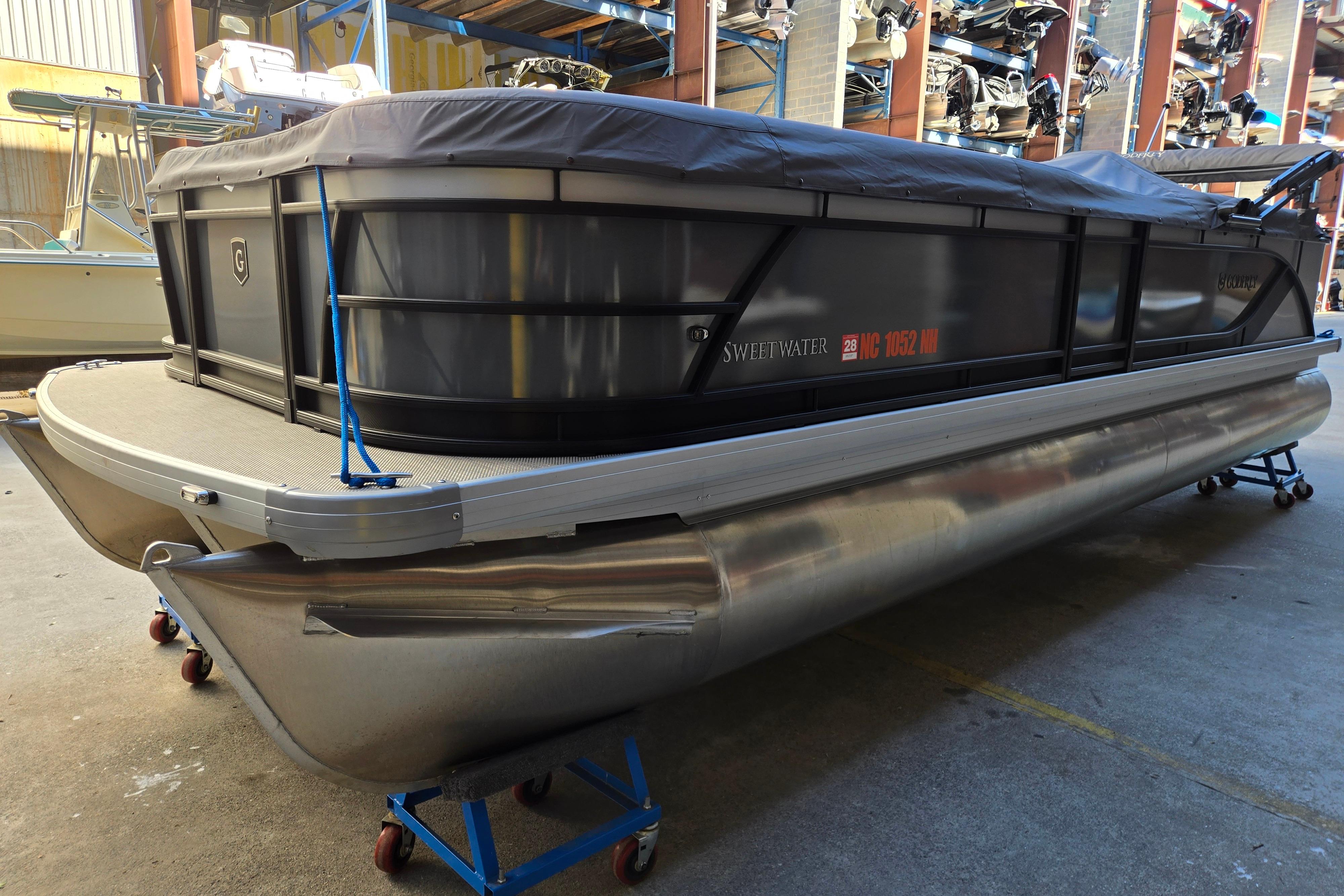 2024 Godfrey Sweetwater 2486 SB pontoon boat in storage, covered and elevated on stands.