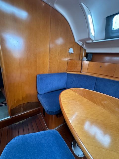 Interior of 1997 Beneteau 42S7 sailboat with blue seating and wooden table.