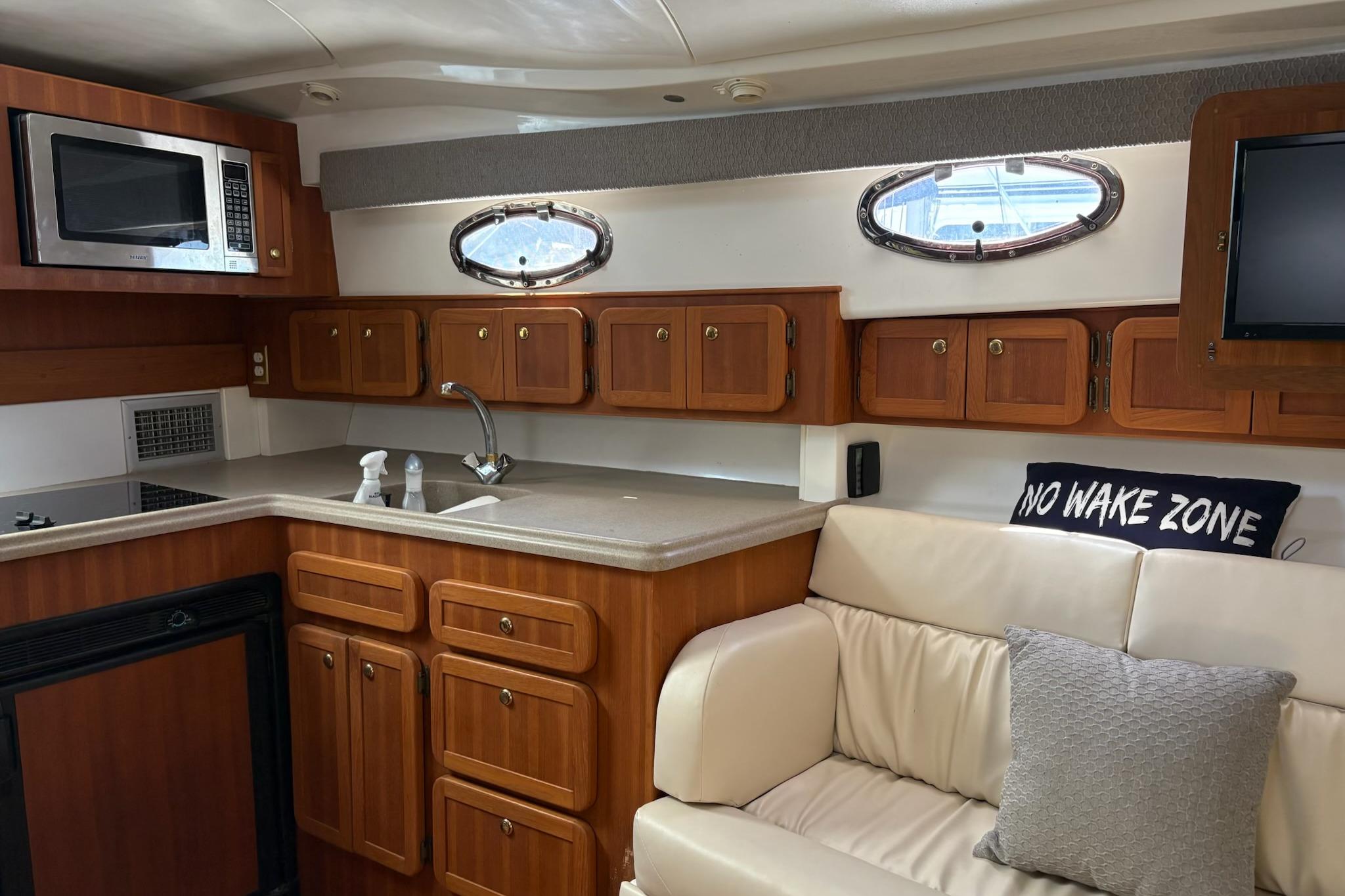 2008 Stamas 370 Express yacht interior with kitchenette, wooden cabinets, and cozy seating area.