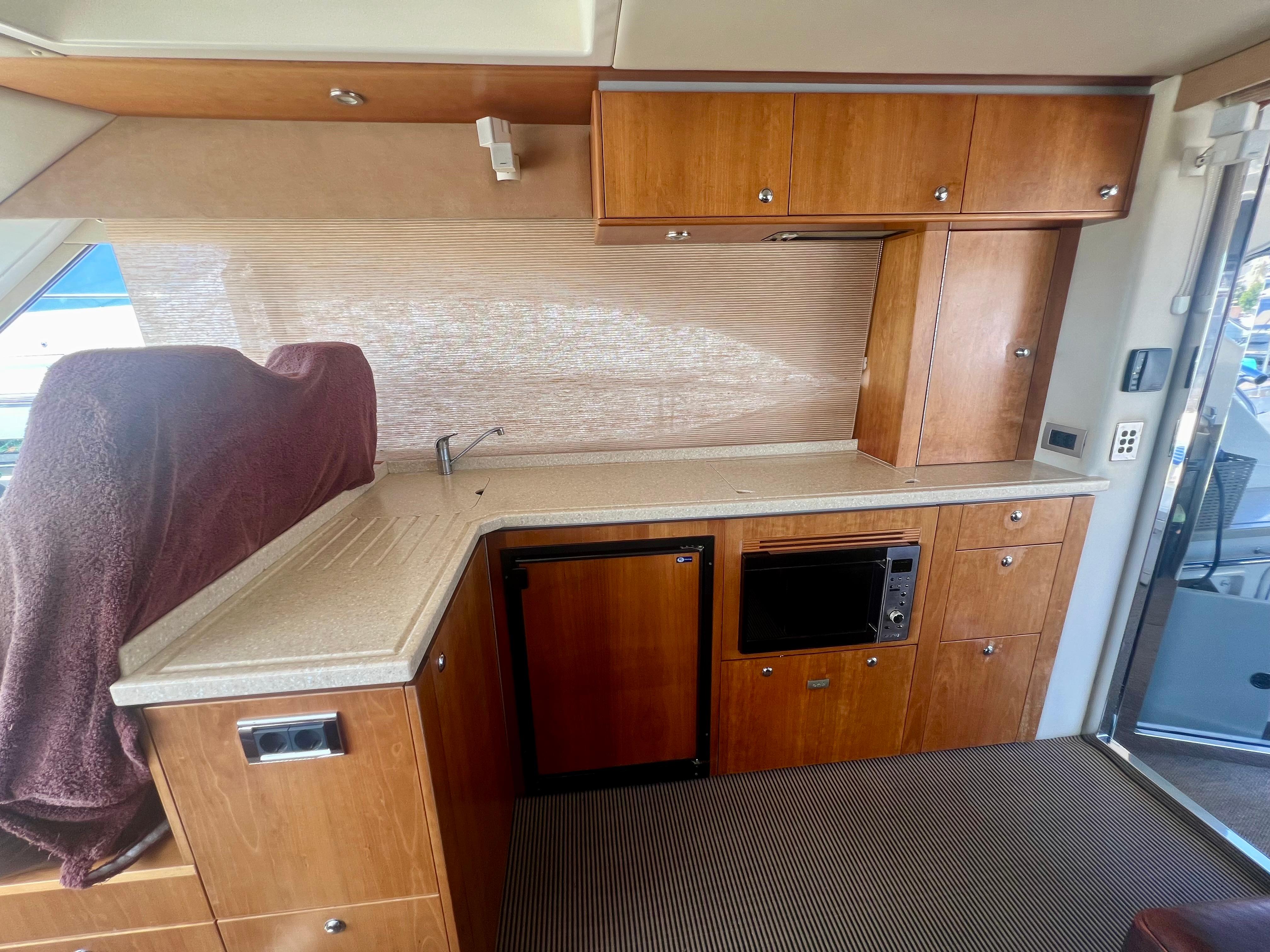 2008 Riviera 4700 Sport Yacht interior kitchen with wood cabinetry and modern appliances.