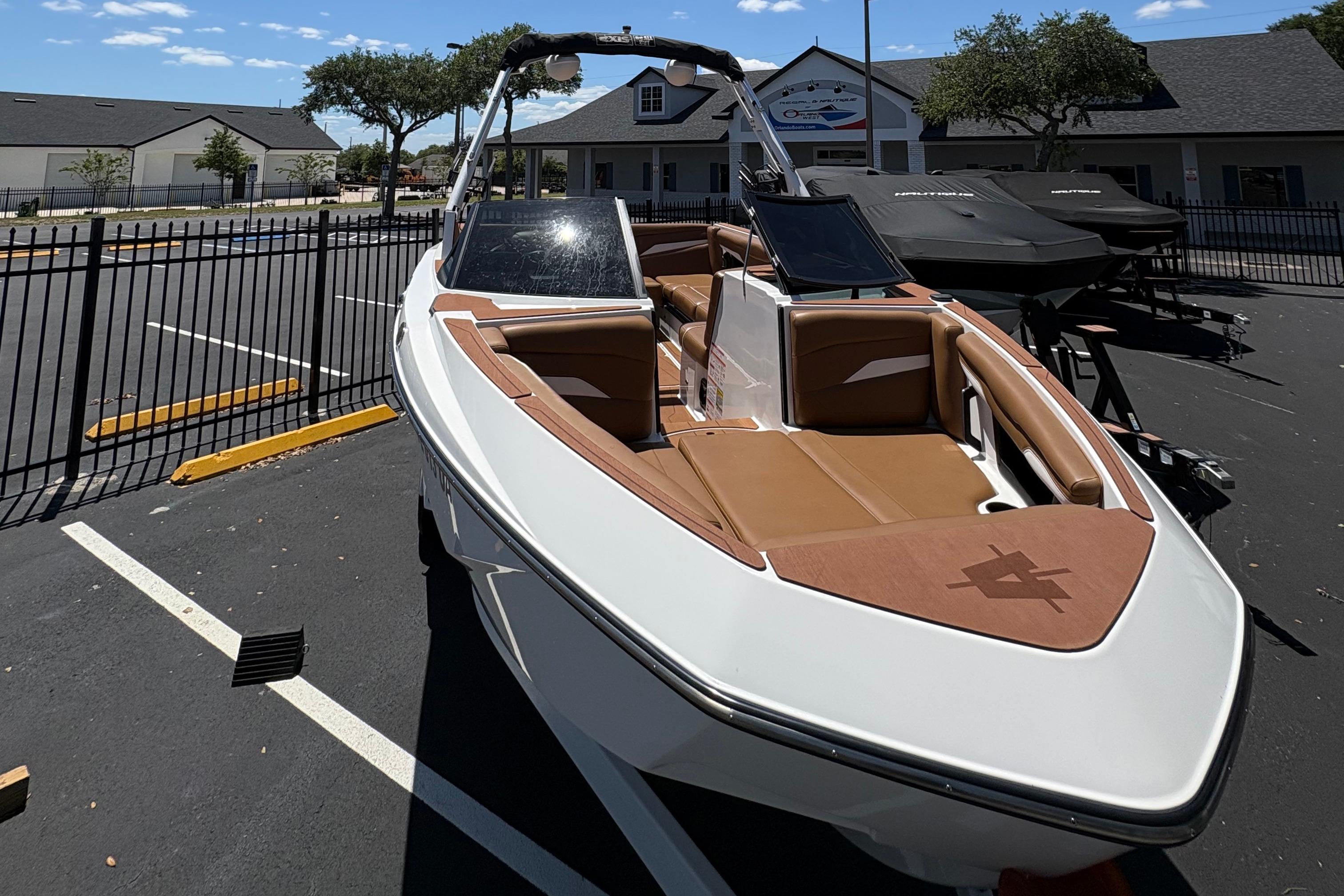 2025 Axis T220 boat with brown interior, parked outdoors near a fence.