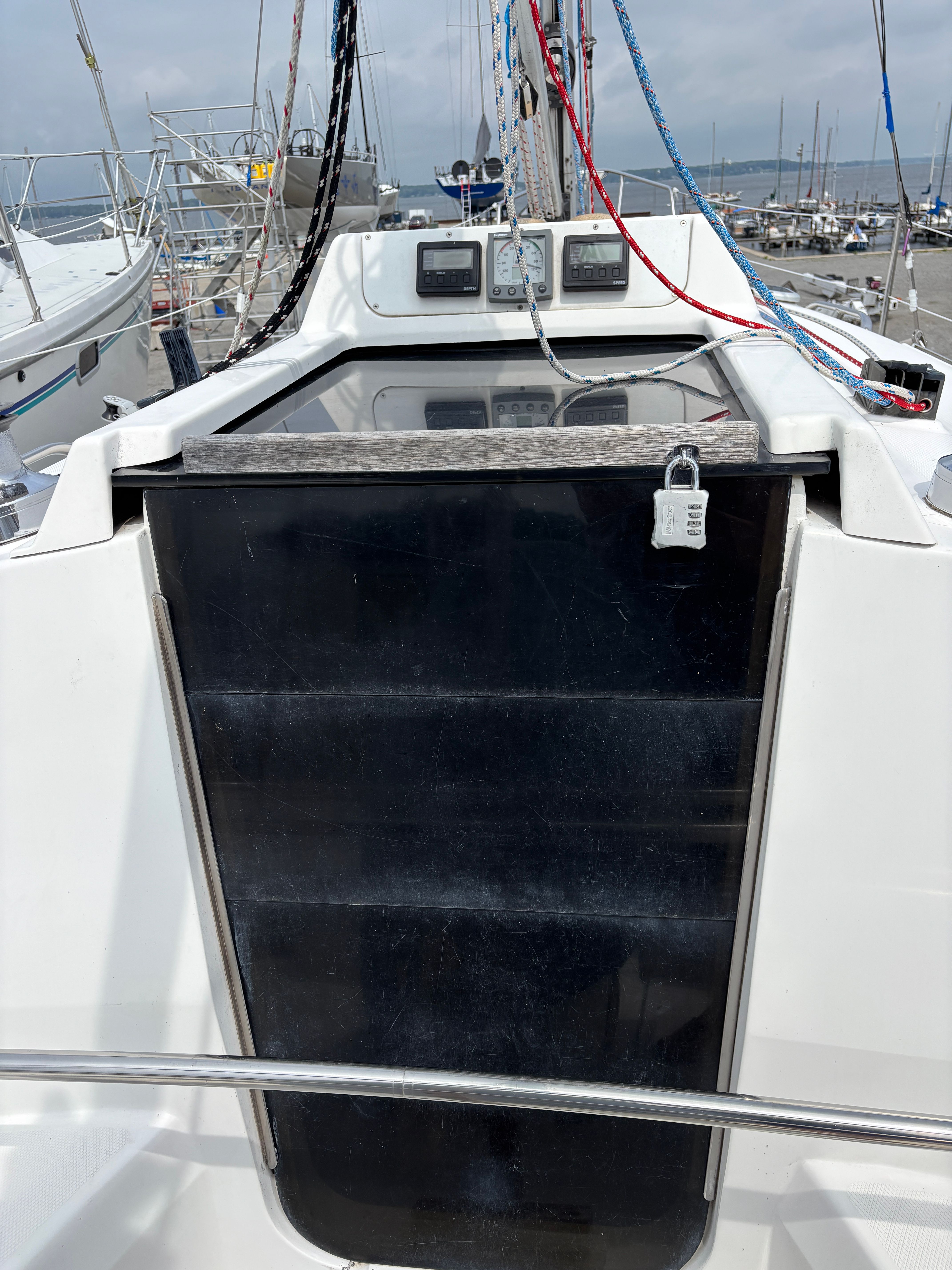 Sailboat cockpit of a 2001 Hunter 320 with secured hatch and visible rigging.