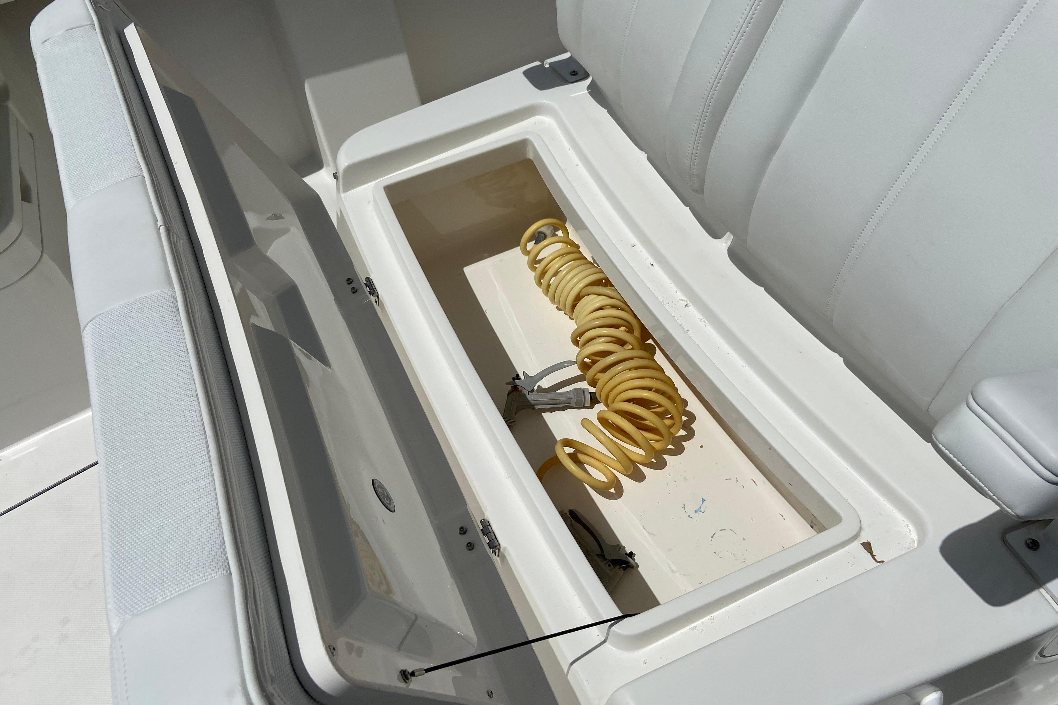 Open storage compartment on 2021 Regulator 28 boat with coiled yellow hose.