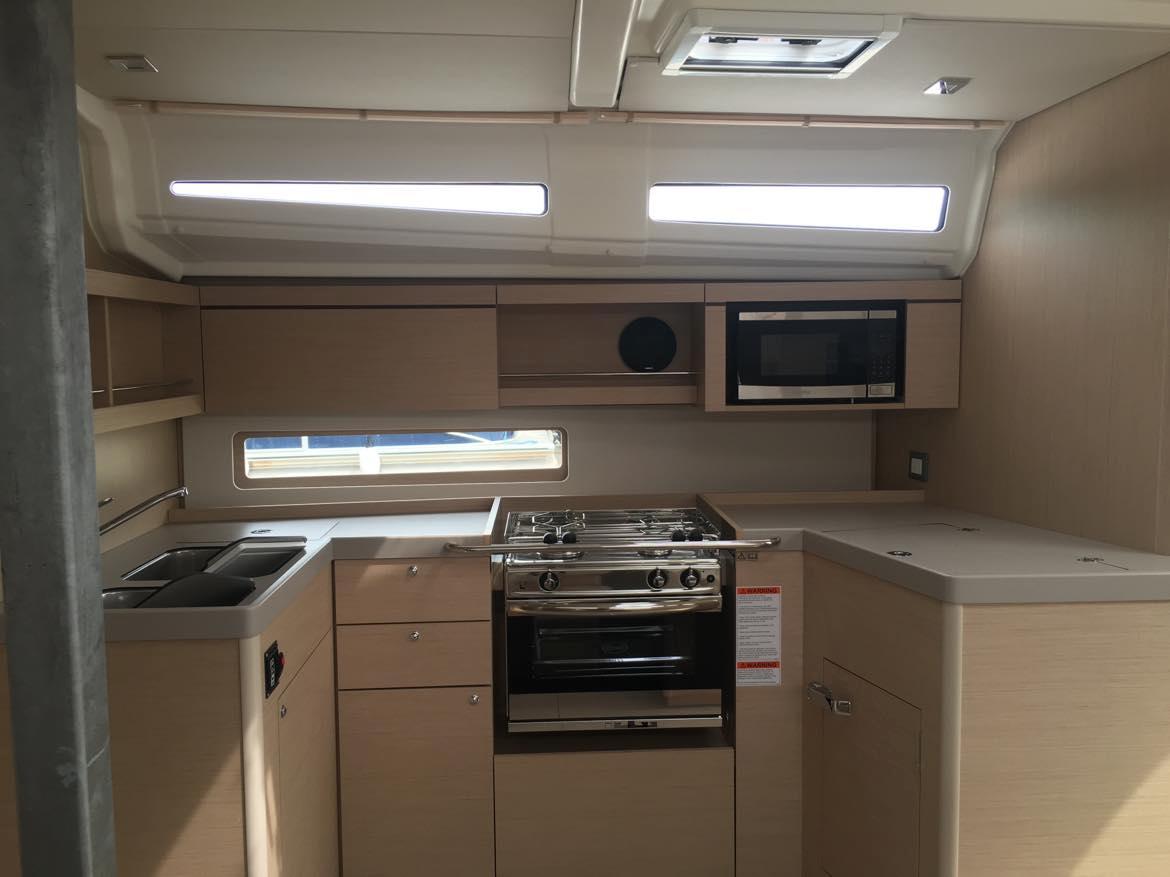 Modern kitchen interior of 2025 Beneteau Oceanis 40.1 yacht with stove and microwave.