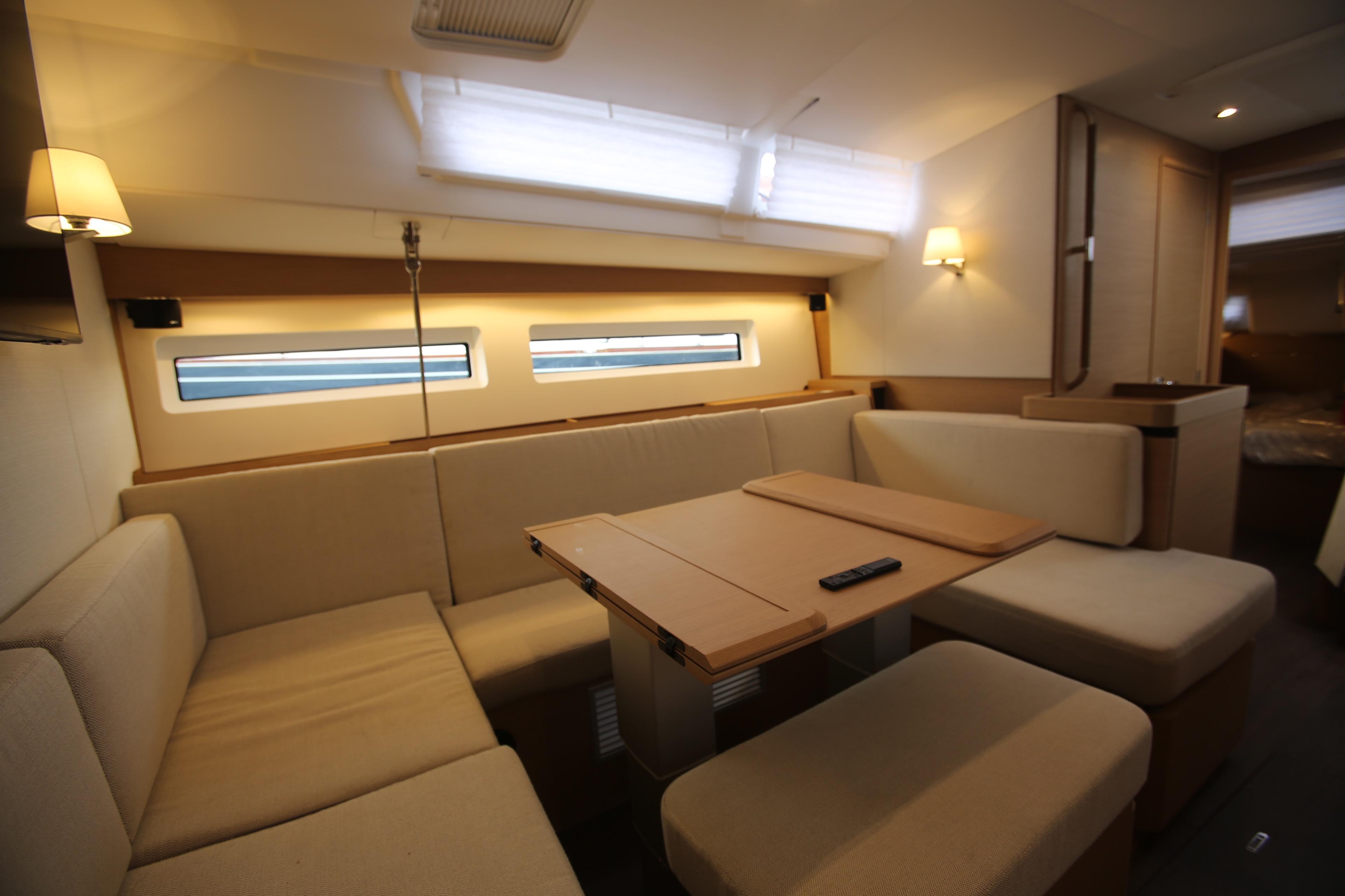 Interior of 2023 Jeanneau Sun Odyssey 490 yacht, featuring a cozy dining area with beige seating.