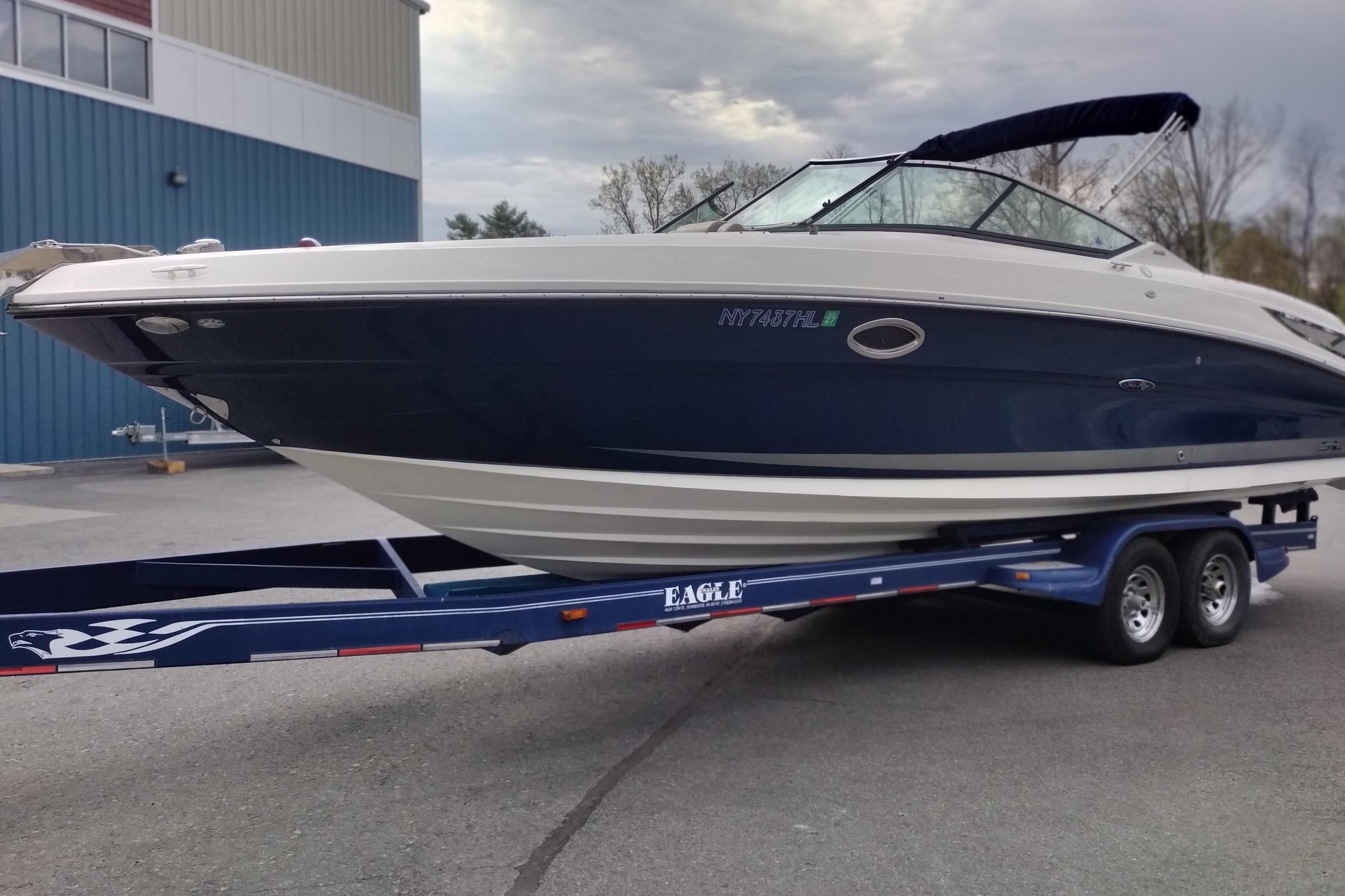 2013 Sea Ray 300 SLX boat on trailer, parked outdoors near a blue building.