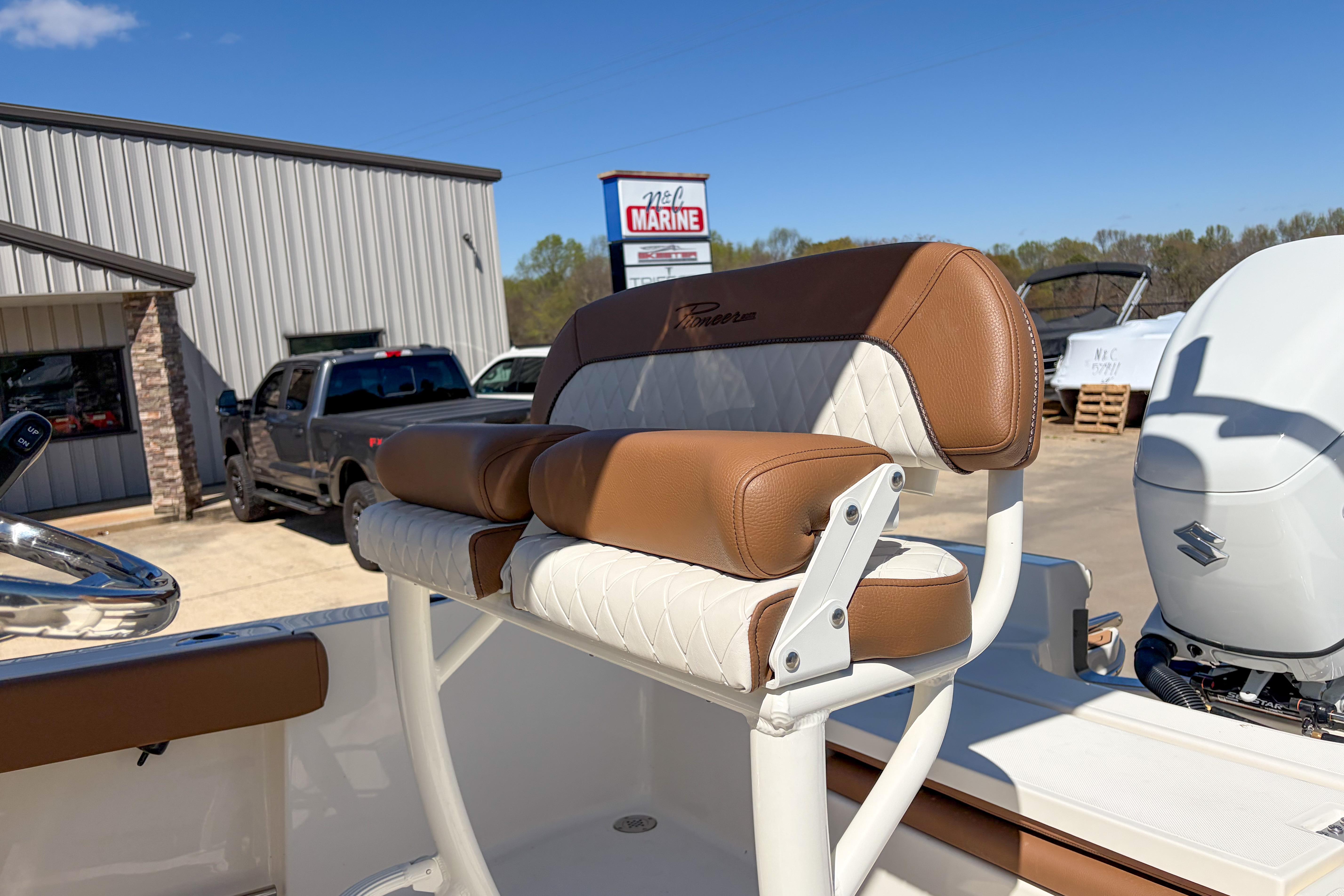 2026 Pioneer 220 Bay Sport boat seat with brown and white upholstery at a marina.